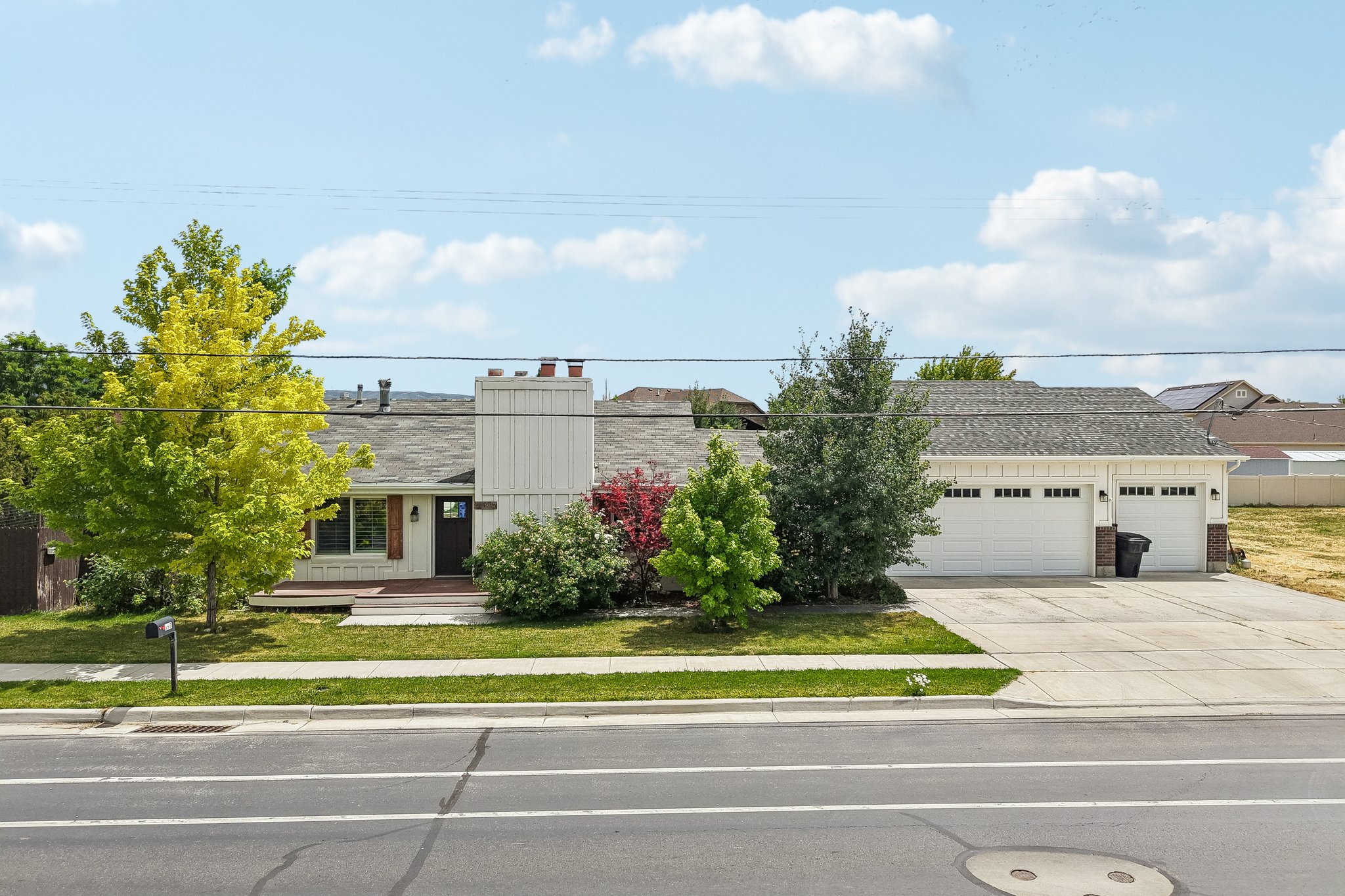 Exterior with a two-car garage featuring white paneled doors, a gray shingle roof, and a concrete driveway