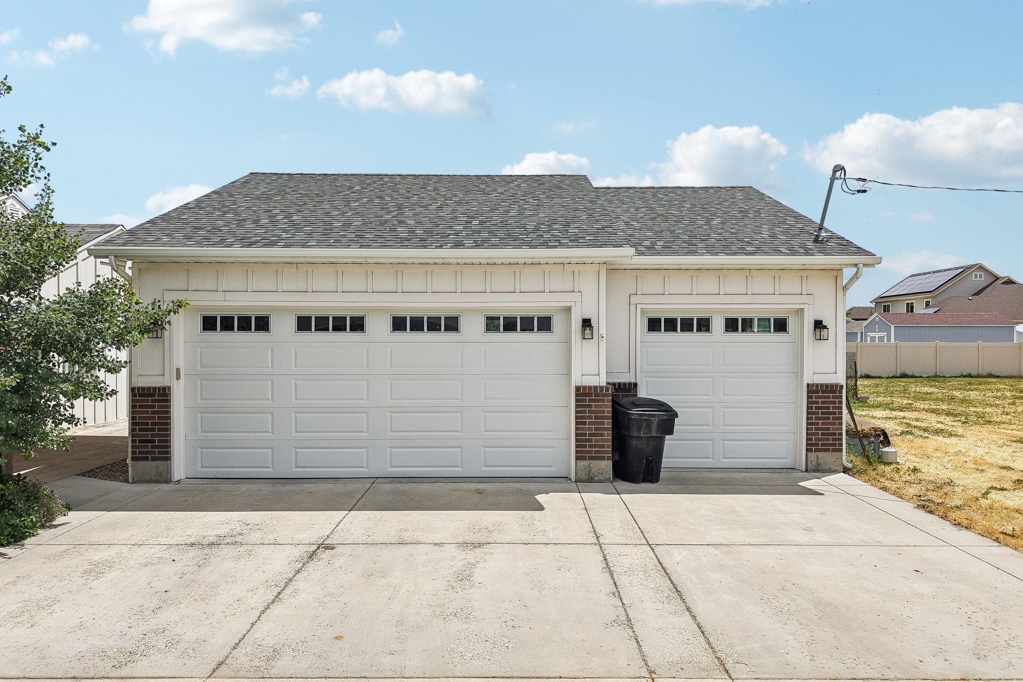 Two-car garage featuring white panel doors with upper window inserts, board and batten siding, and brick accents