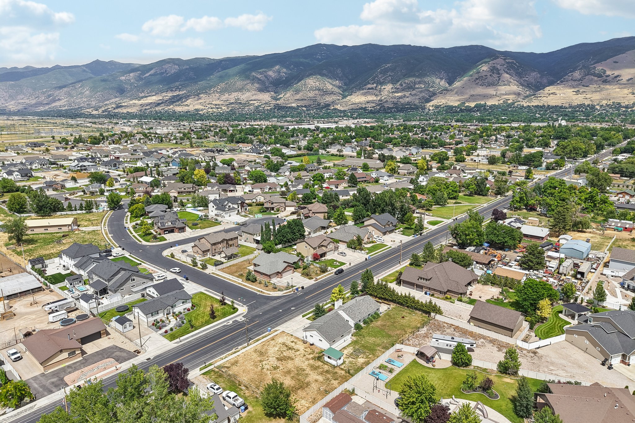 Expansive residential area featuring a curvilinear street layout, mature landscaping, and mountain backdrops