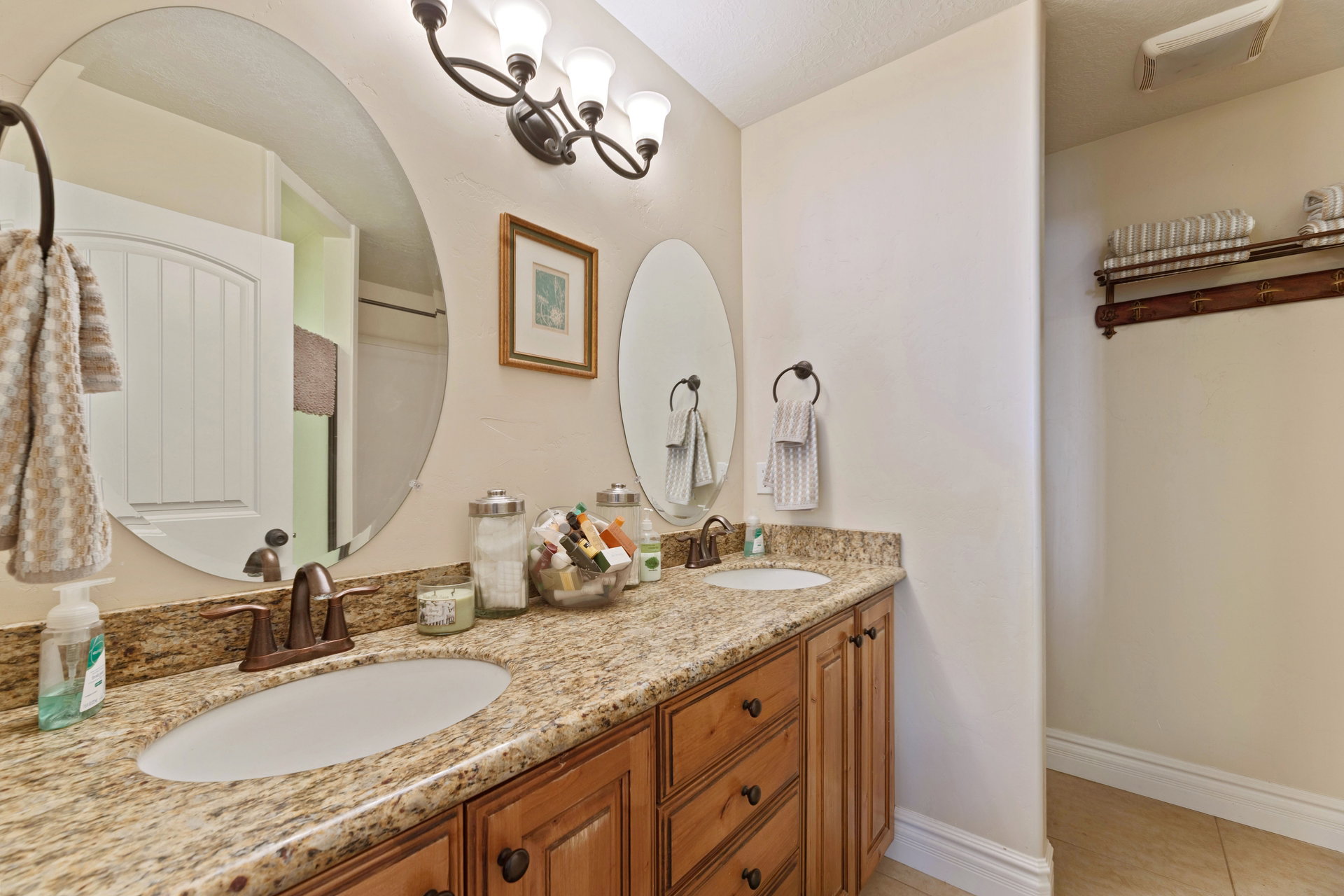 Dual oval mirrors above a granite-finish double vanity with integrated sinks