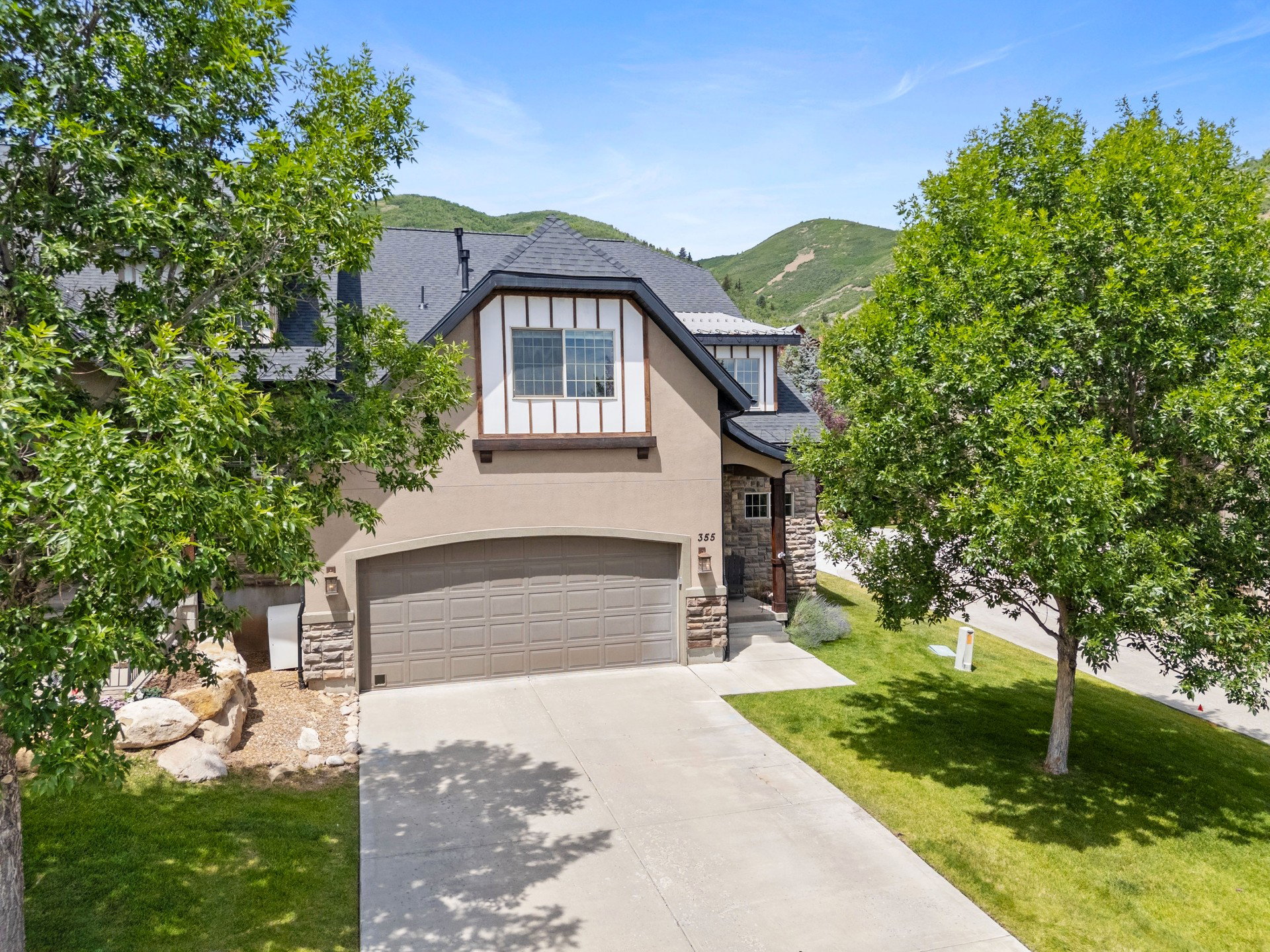 Mountain Contemporary stucco townhome featuring stone accents, a two-car garage, and a concrete driveway