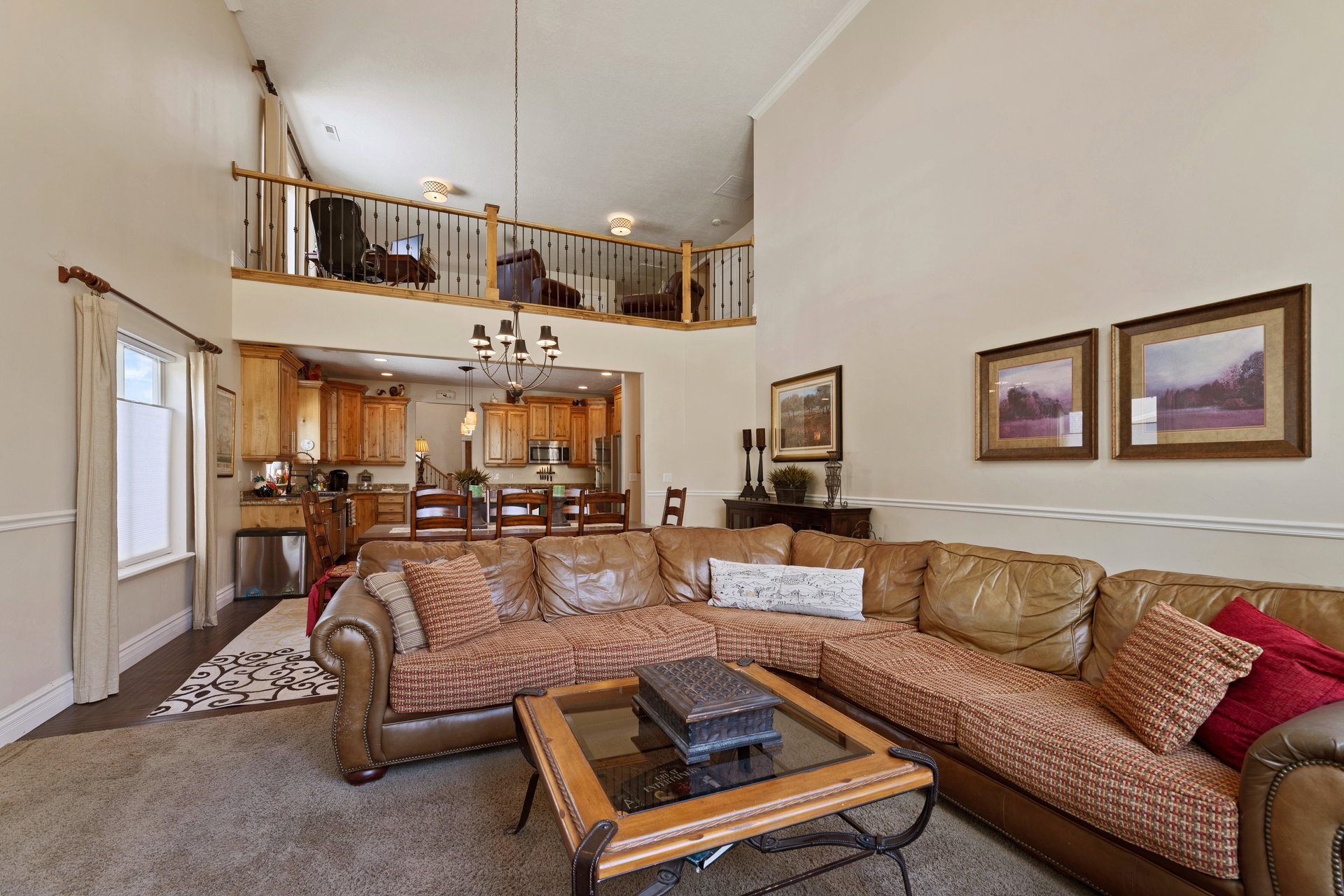 Open-concept living area featuring a double-height ceiling, hardwood flooring, and a kitchen with wood cabinetry