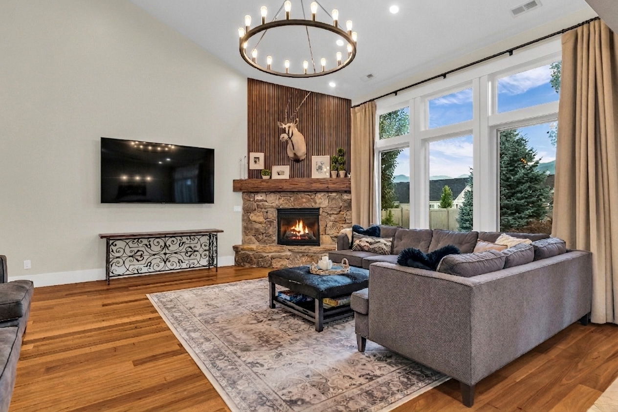 Living area featuring a stone fireplace with a wood-plank accent wall, vaulted ceilings, and a large chandelier