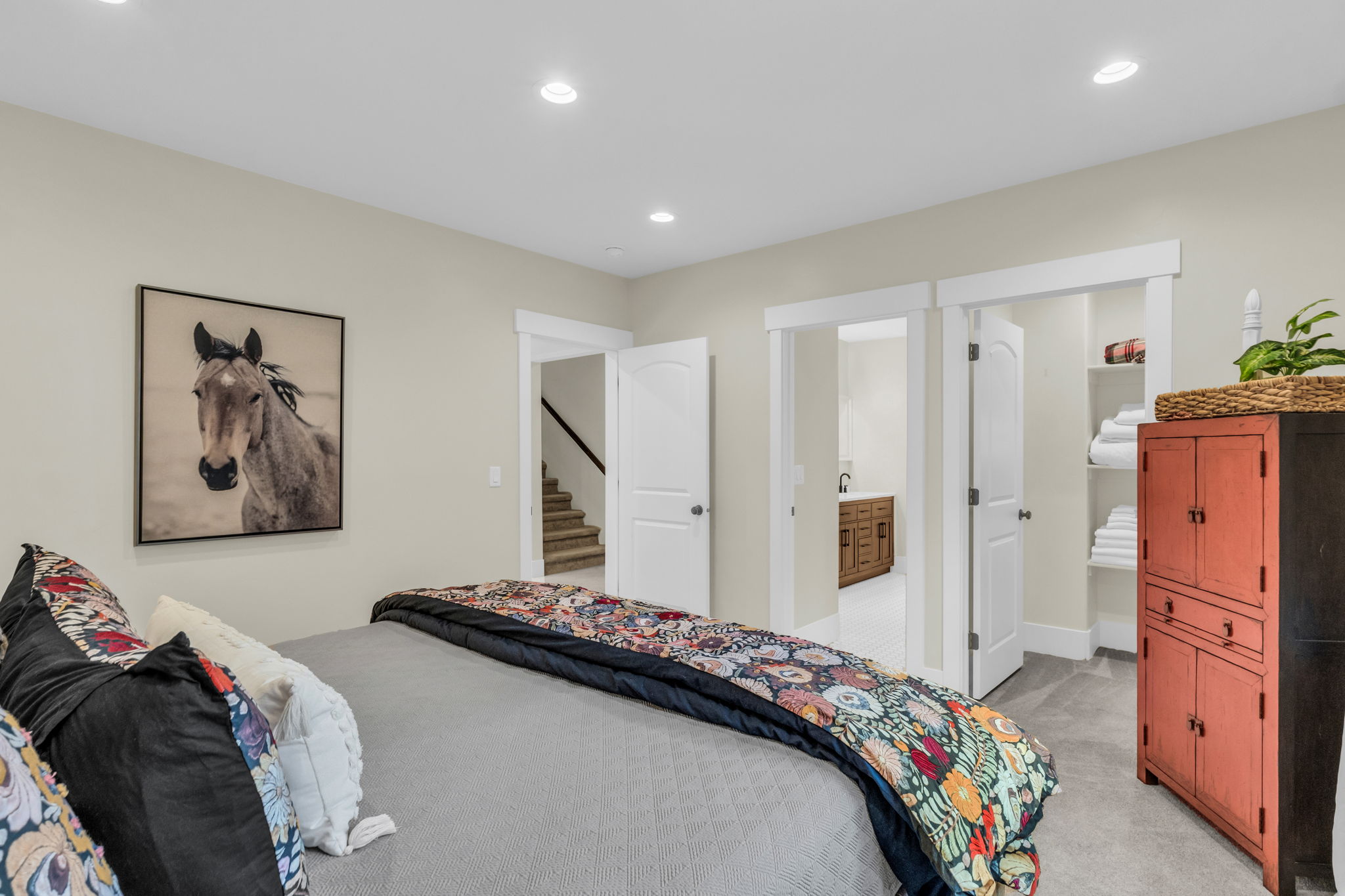 Recessed lighting illuminates the carpeted room, featuring solid core doors with white trim