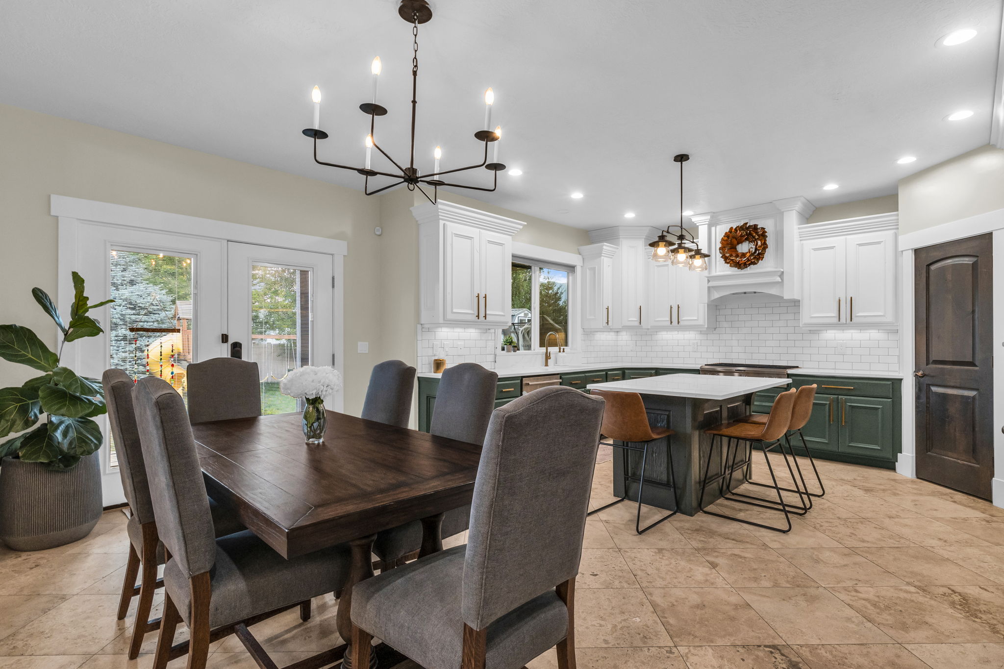 Open-concept kitchen and dining area featuring a two-tone cabinetry design, subway tile backsplash, and a central island with countertop seating