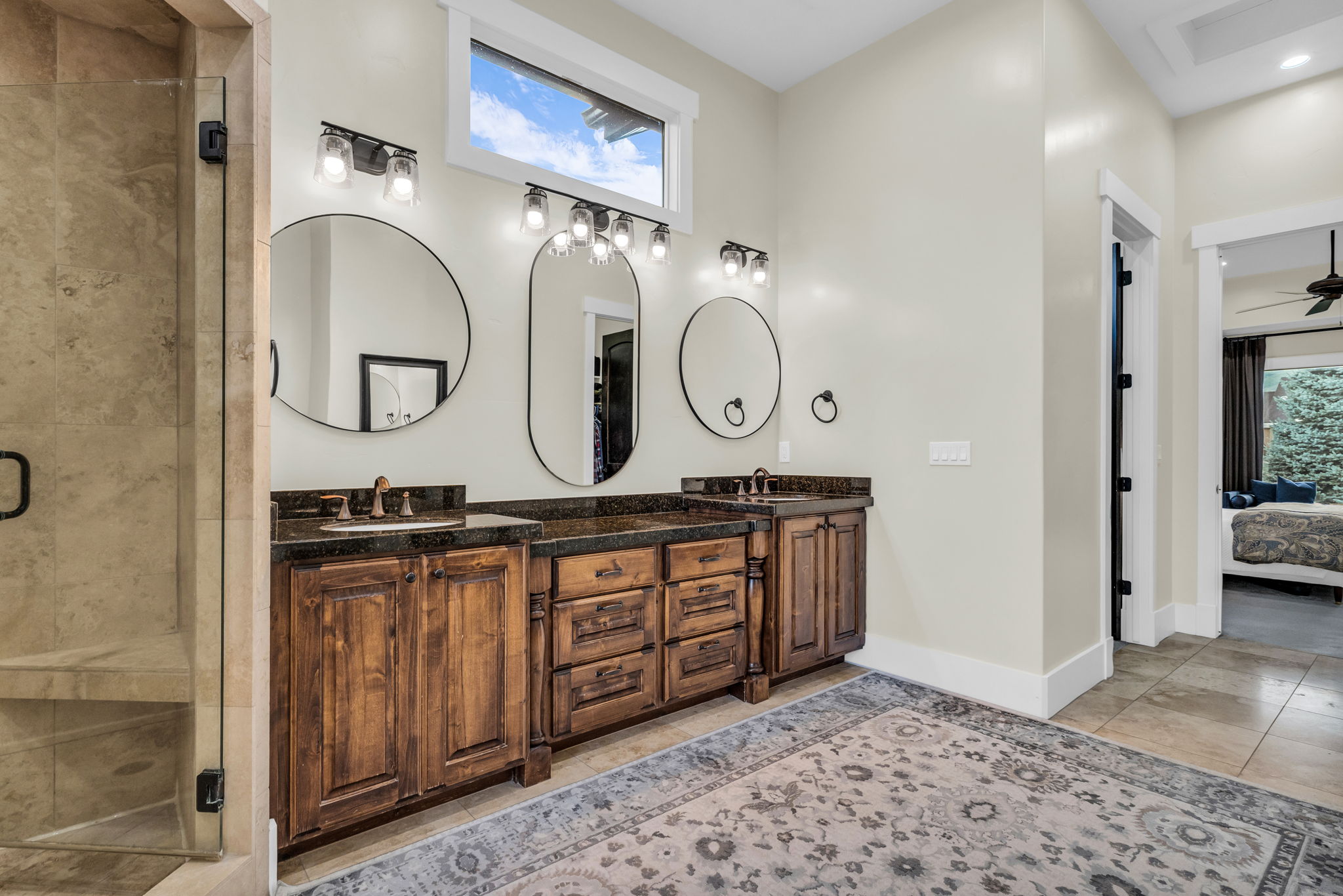 Double vanity featuring dark wood cabinetry, dark countertops, and undermount sinks