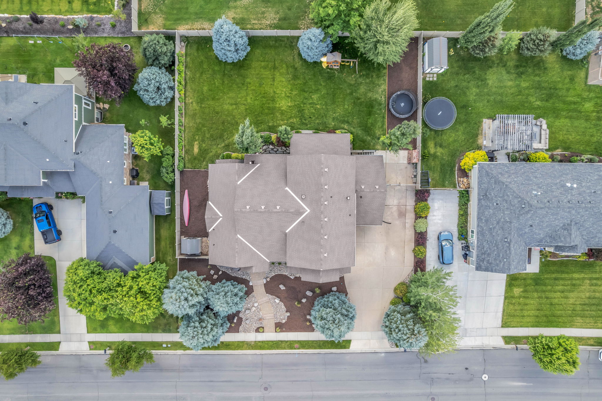 Aerial perspective highlighting a residential property with a multi-gabled roofline and an expansive front driveway