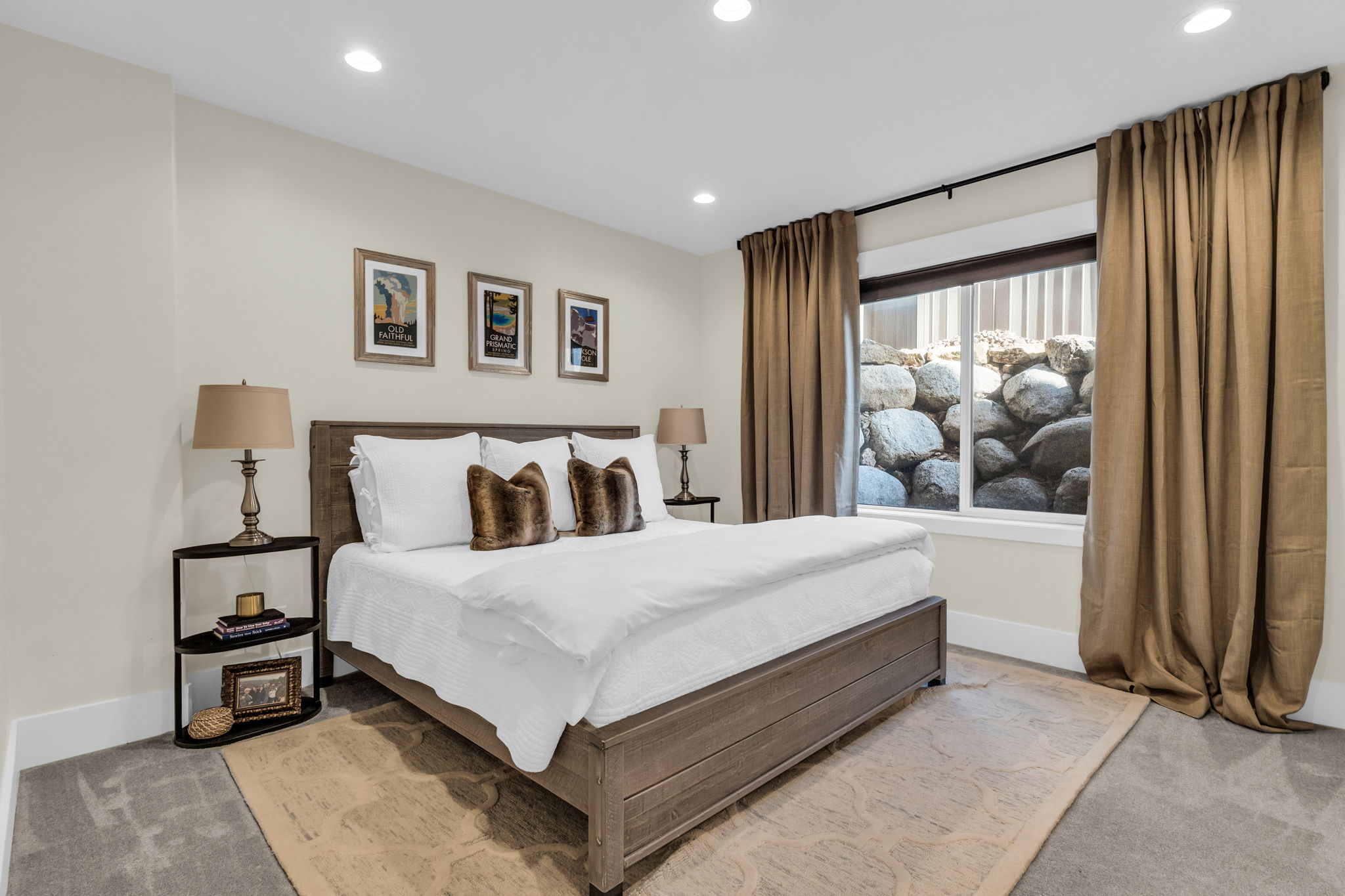 Spacious bedroom featuring recessed lighting, light-colored walls, and a large window with a stone rock feature