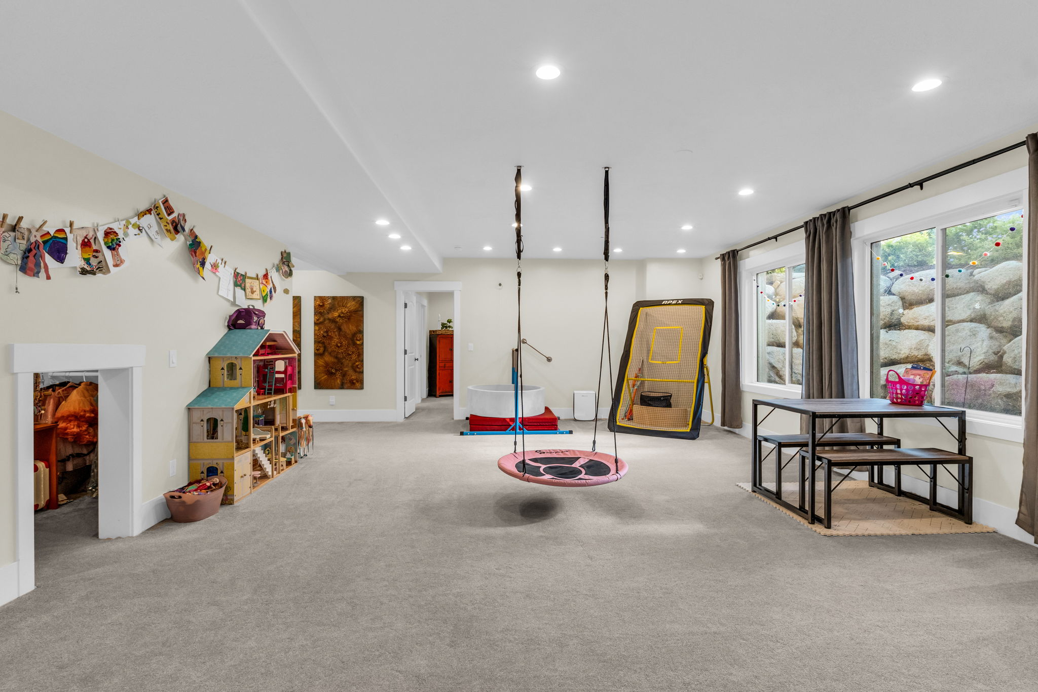 Spacious carpeted room featuring recessed lighting, multiple windows with curtains, and a white trim baseboard