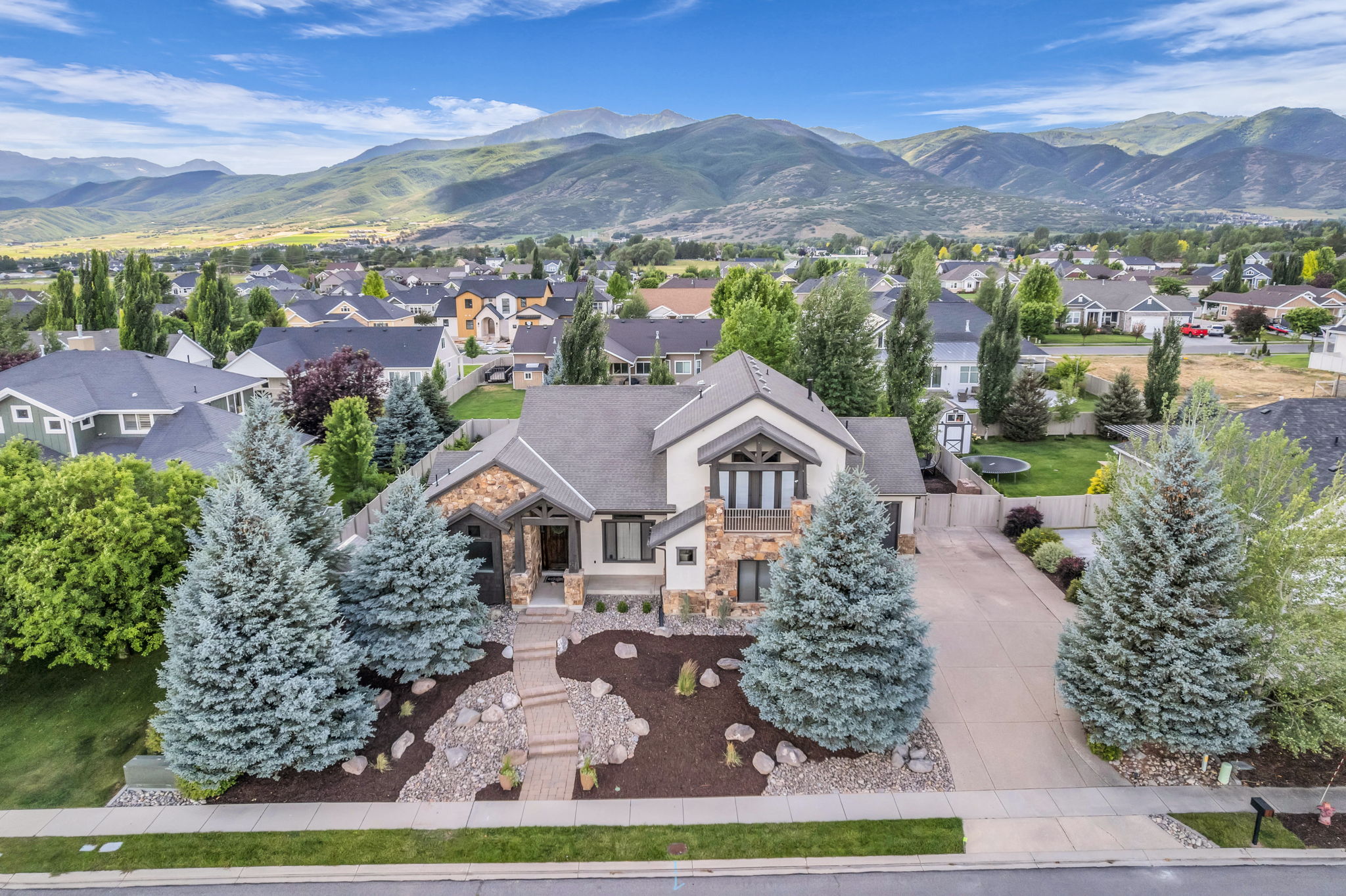 Two-story residence featuring a stone and stucco exterior, prominent entryway, and an attached garage