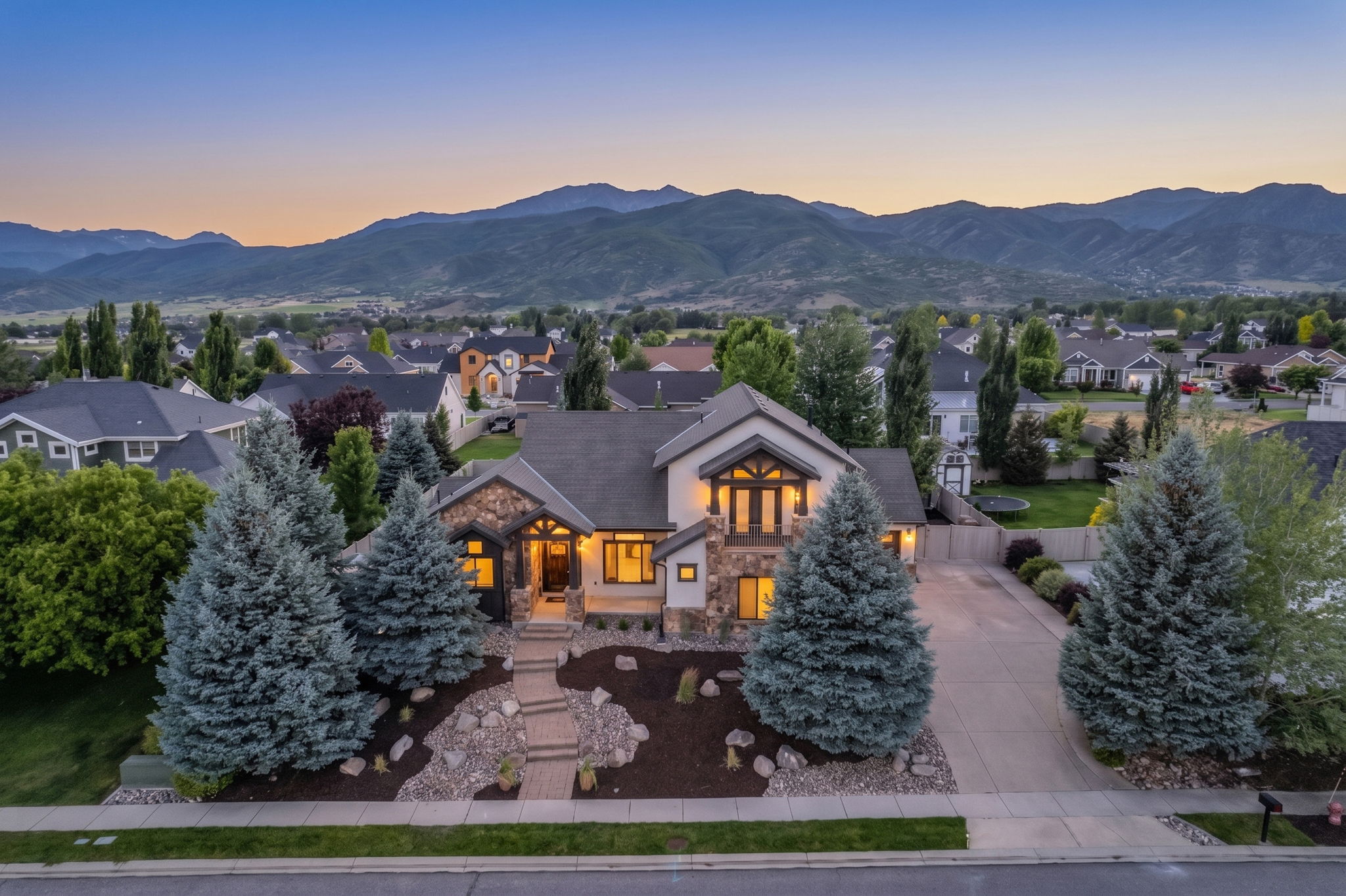 Two-story residence featuring stone and stucco exterior, multiple gables, and an attached two-car driveway
