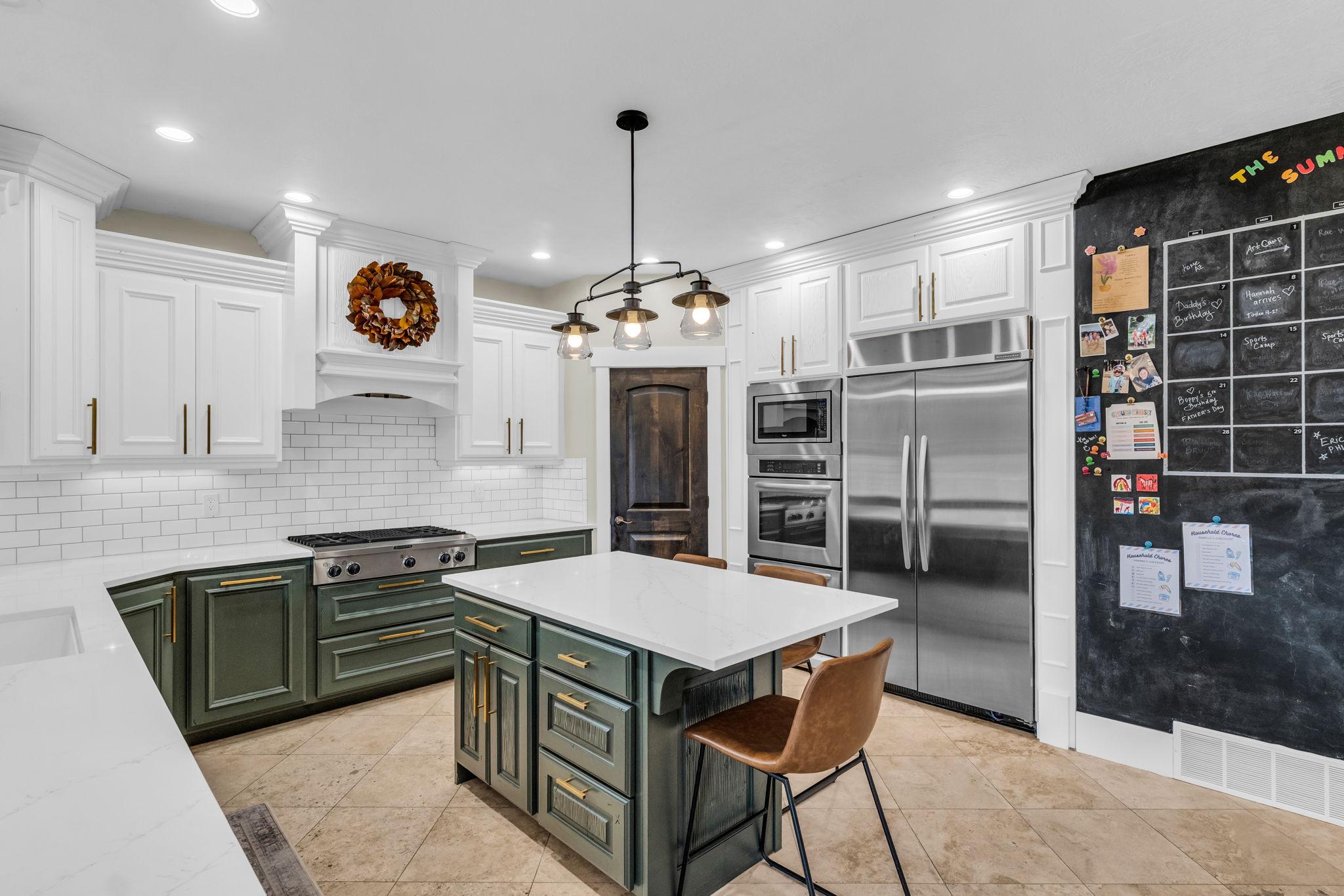Spacious kitchen featuring an expansive island with seating, stainless steel appliance suite, gas range, and white subway tile backsplash