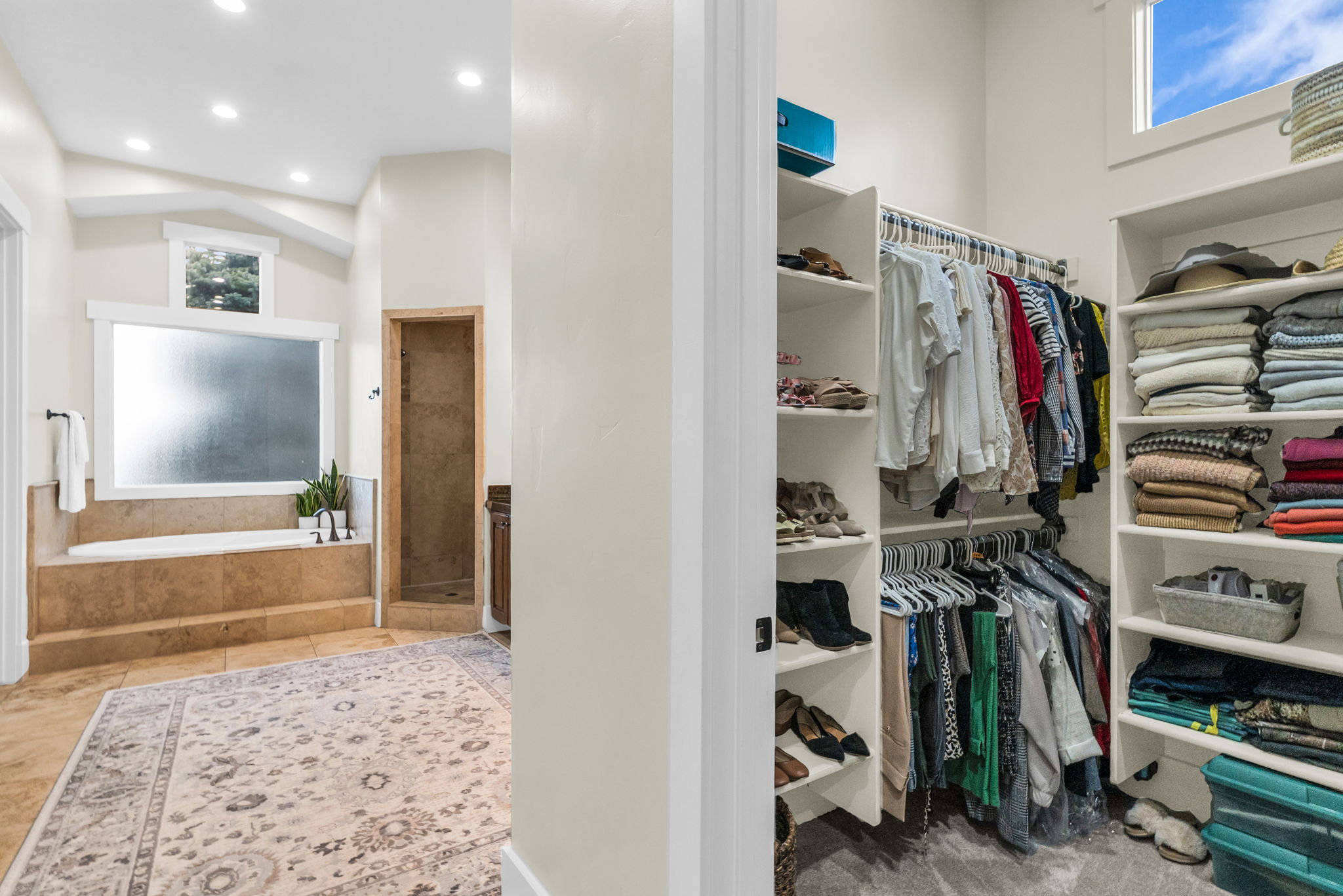Walk-in closet featuring built-in shelving, hanging rods, and a high window