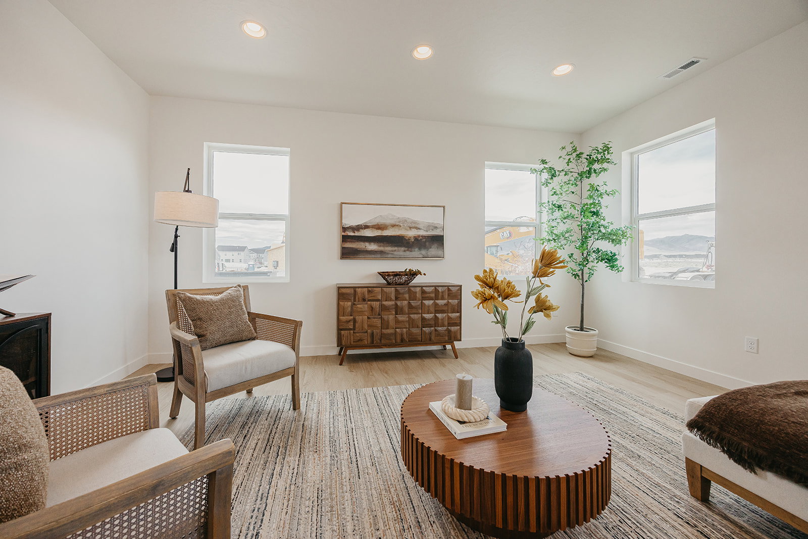 Spacious living area featuring light-toned wood-finish flooring, recessed lighting, and multiple windows