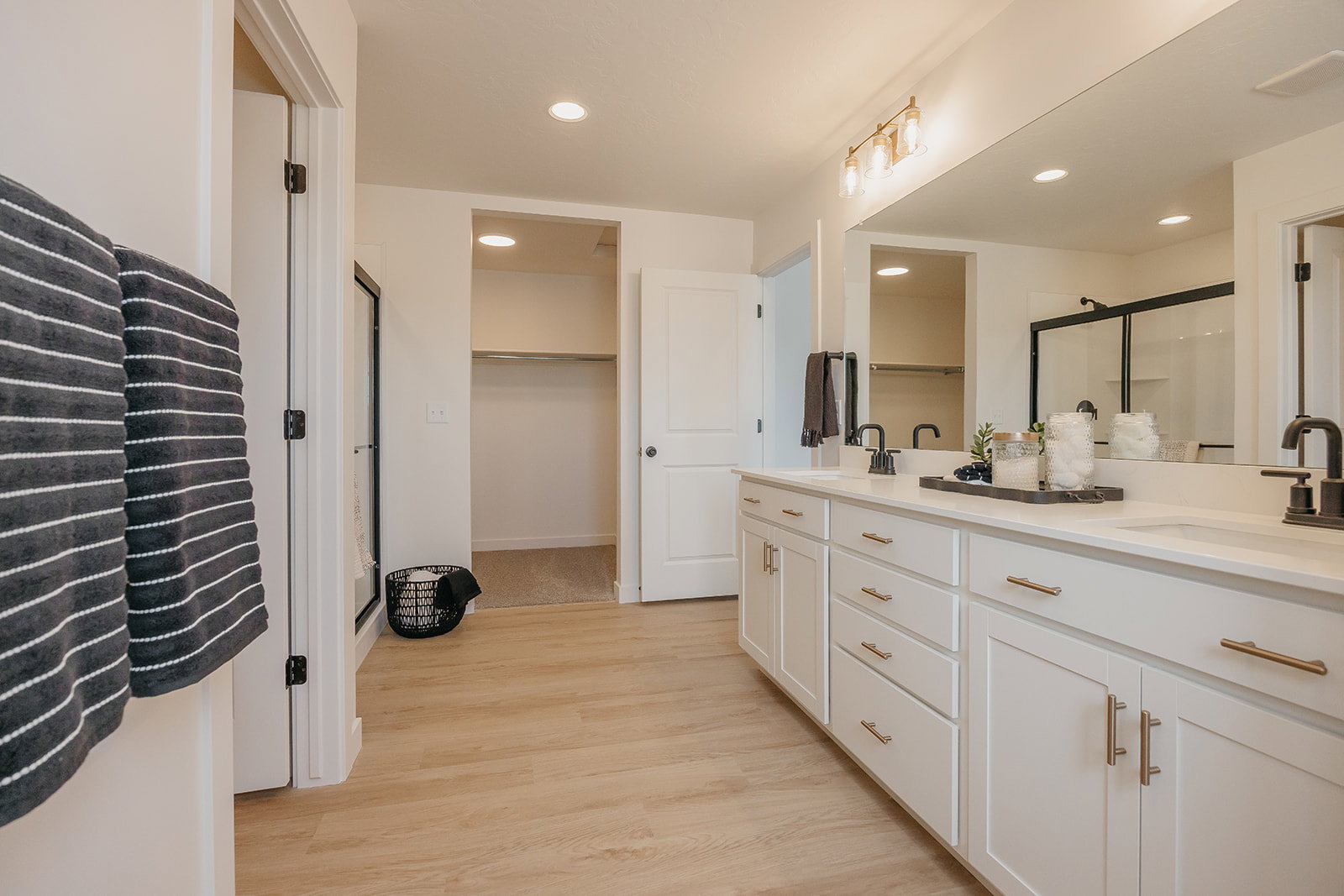 Dual vanity with white cabinetry, matte black fixtures, and a large mirror