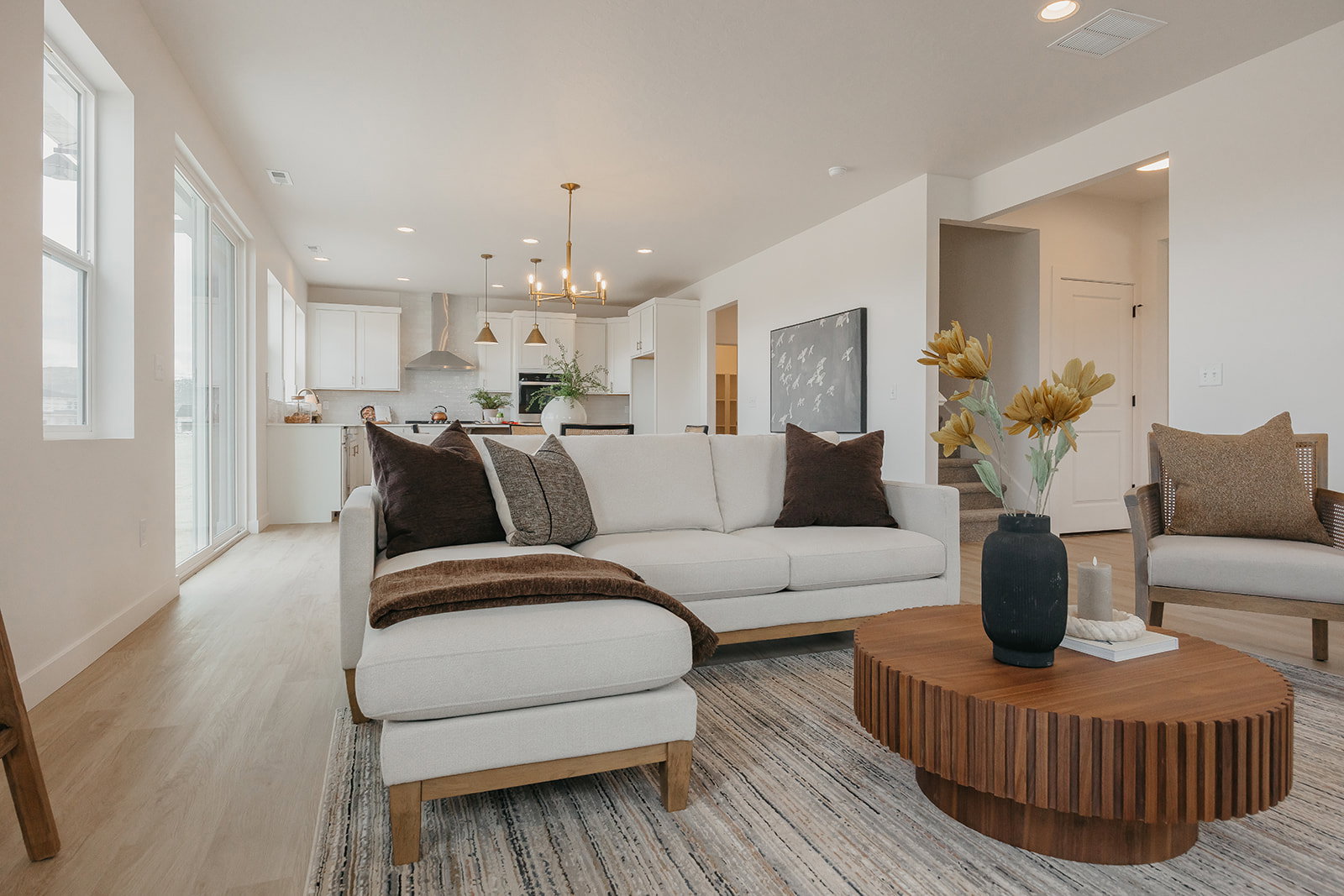 Open-concept living space featuring wood-finish flooring, recessed lighting, and a modern kitchen with a stainless steel range hood