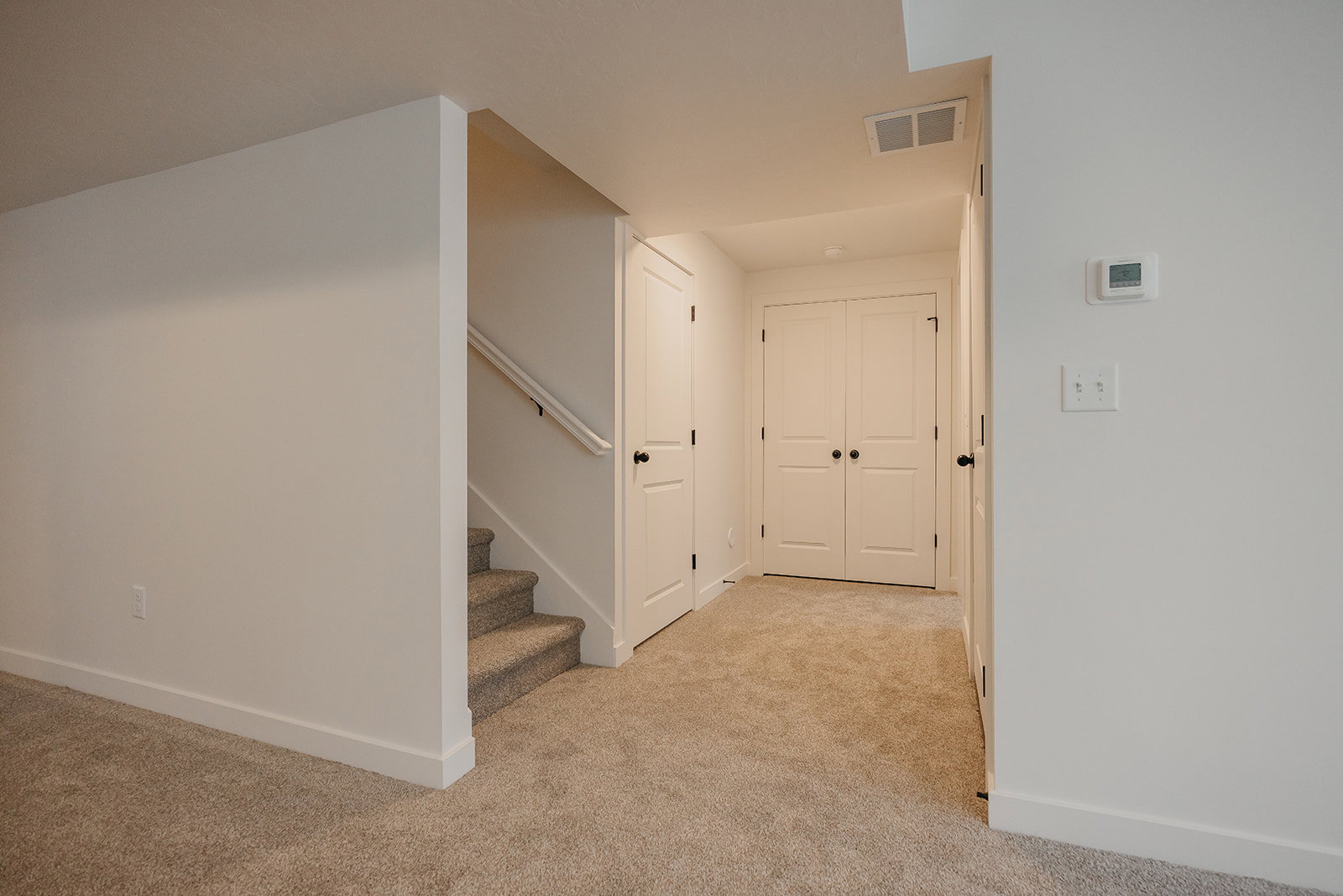 Interior hallway featuring neutral carpet flooring, white walls, and white trim