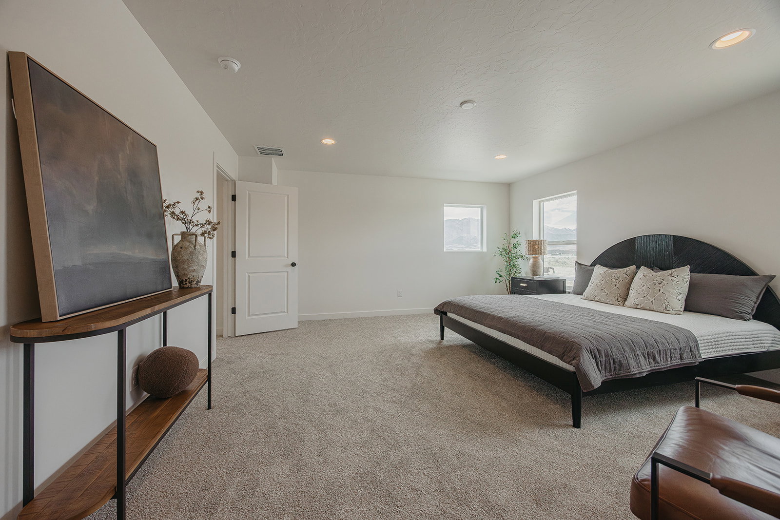 Spacious bedroom featuring neutral carpeting, recessed lighting, white walls, and multiple windows