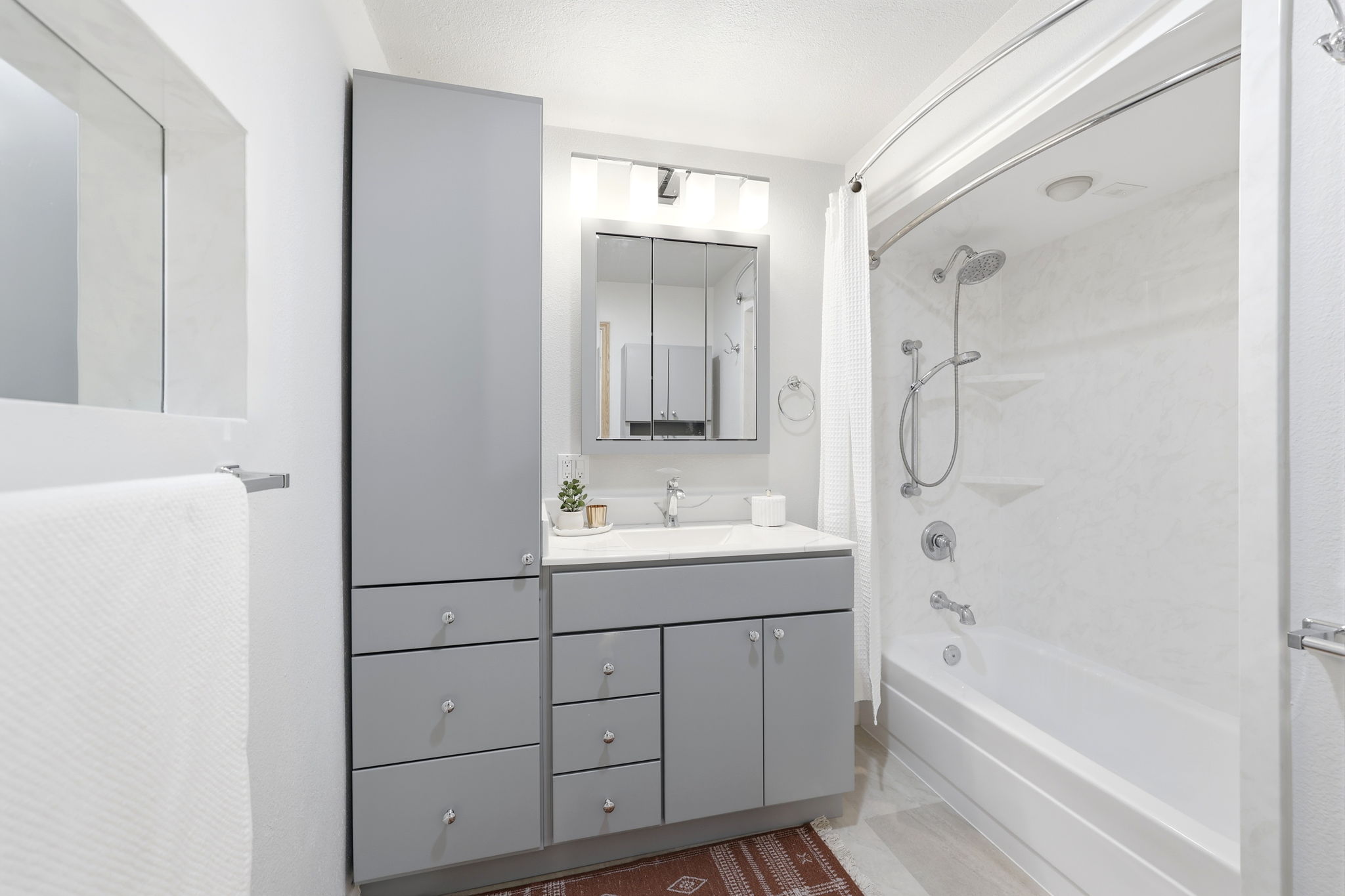 Bathroom featuring a white tub/shower combination with a rainfall showerhead and hand-held sprayer