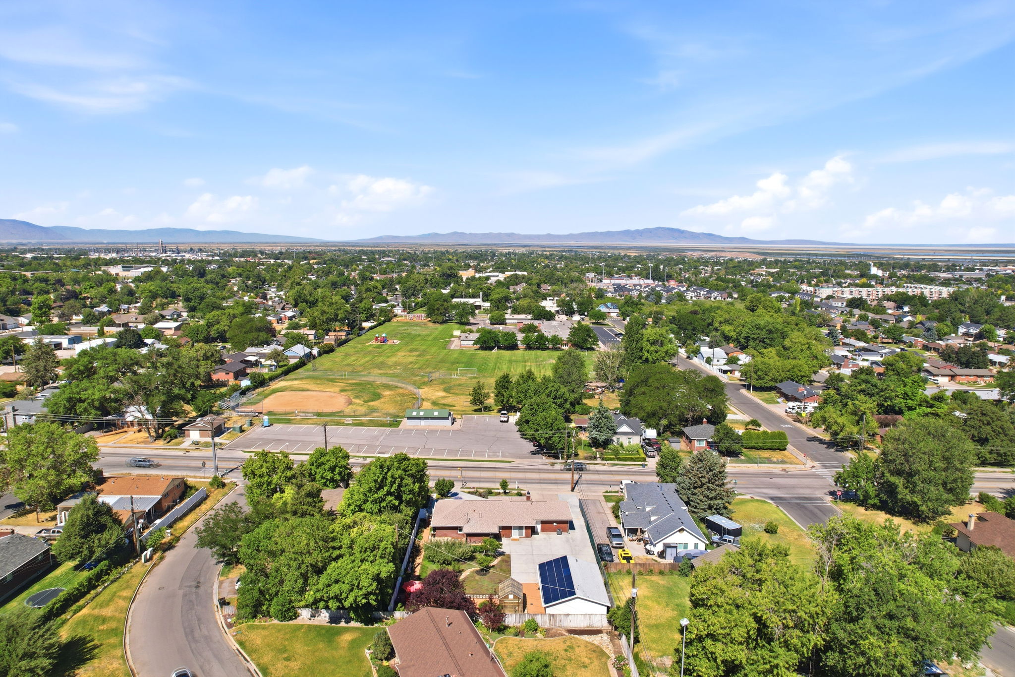 Aerial perspective showcasing a residential area with mature trees and distant mountains