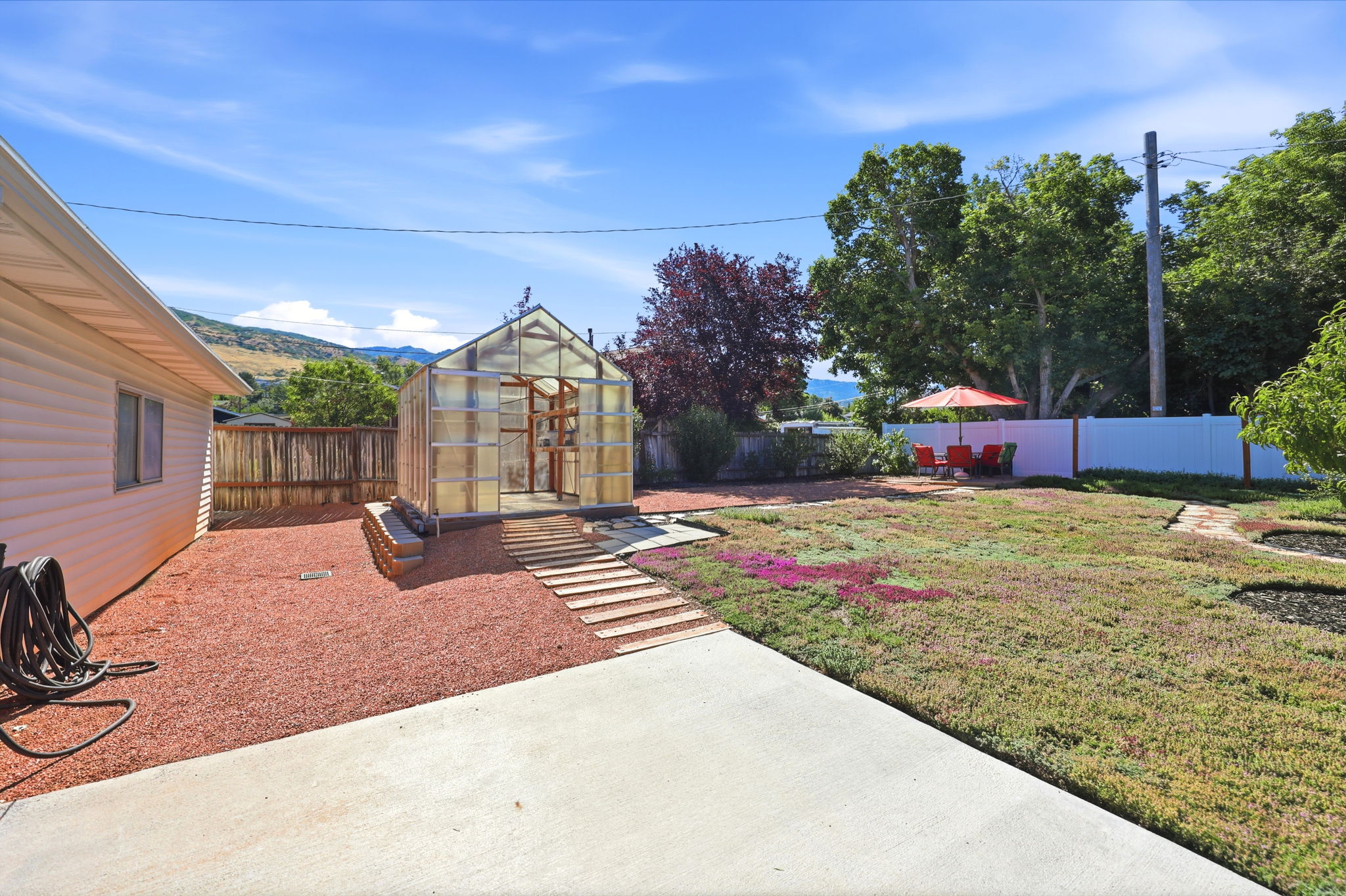 Spacious backyard featuring a greenhouse, concrete patio, and a privacy fence