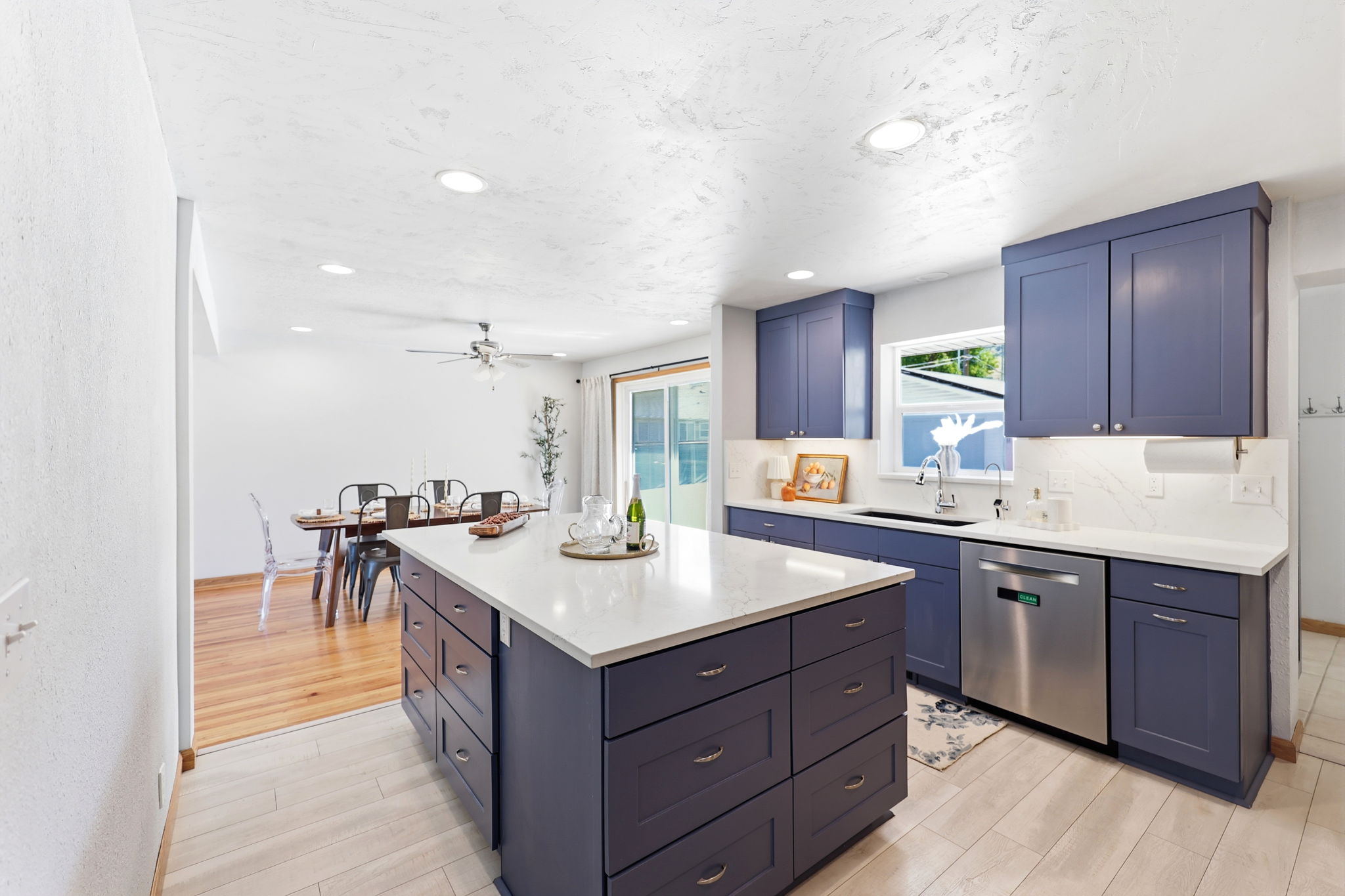 Kitchen featuring a central island with white countertop, blue cabinetry, stainless steel dishwasher, and recessed lighting