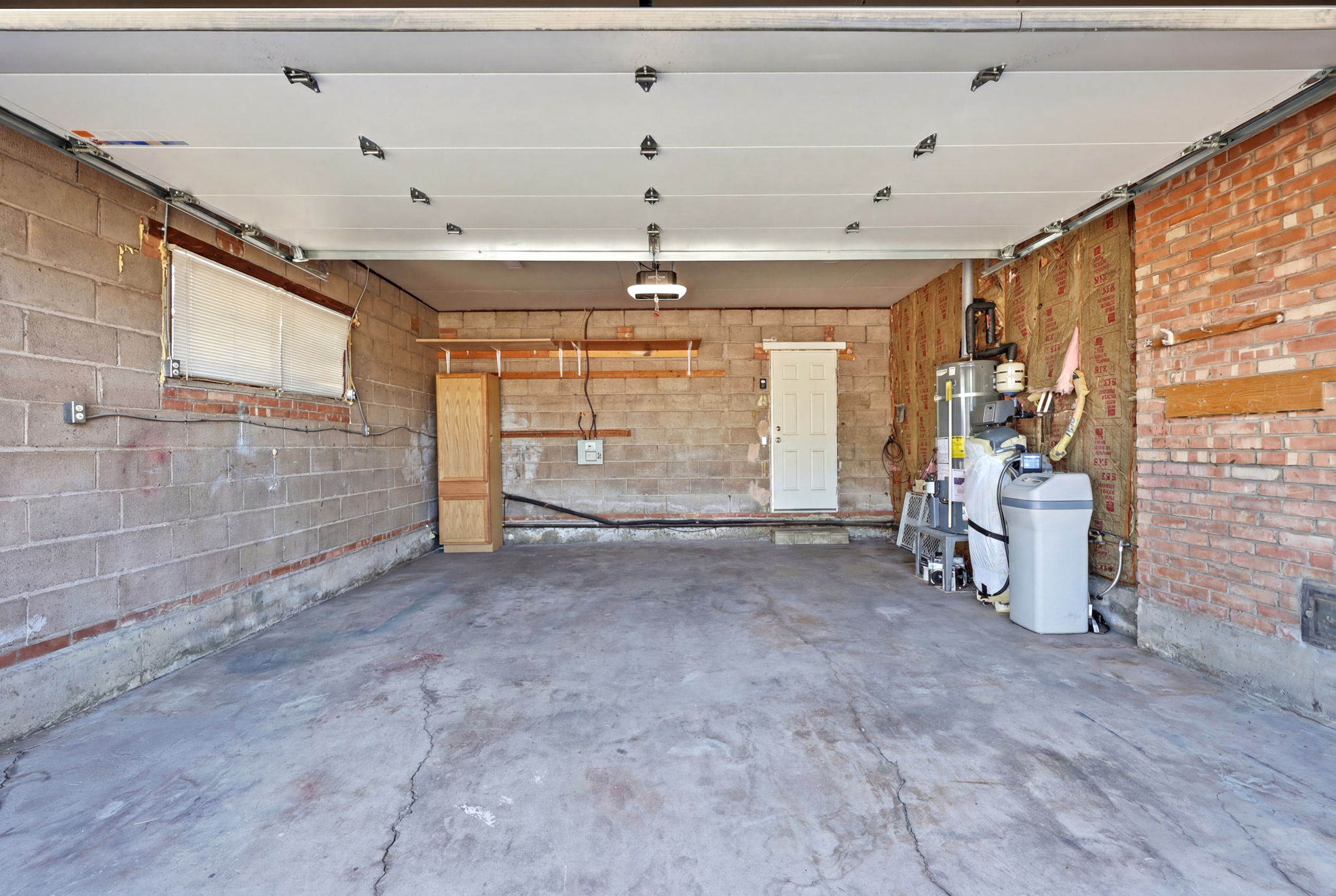 Spacious garage with concrete block walls, exposed brick accents, and a concrete floor