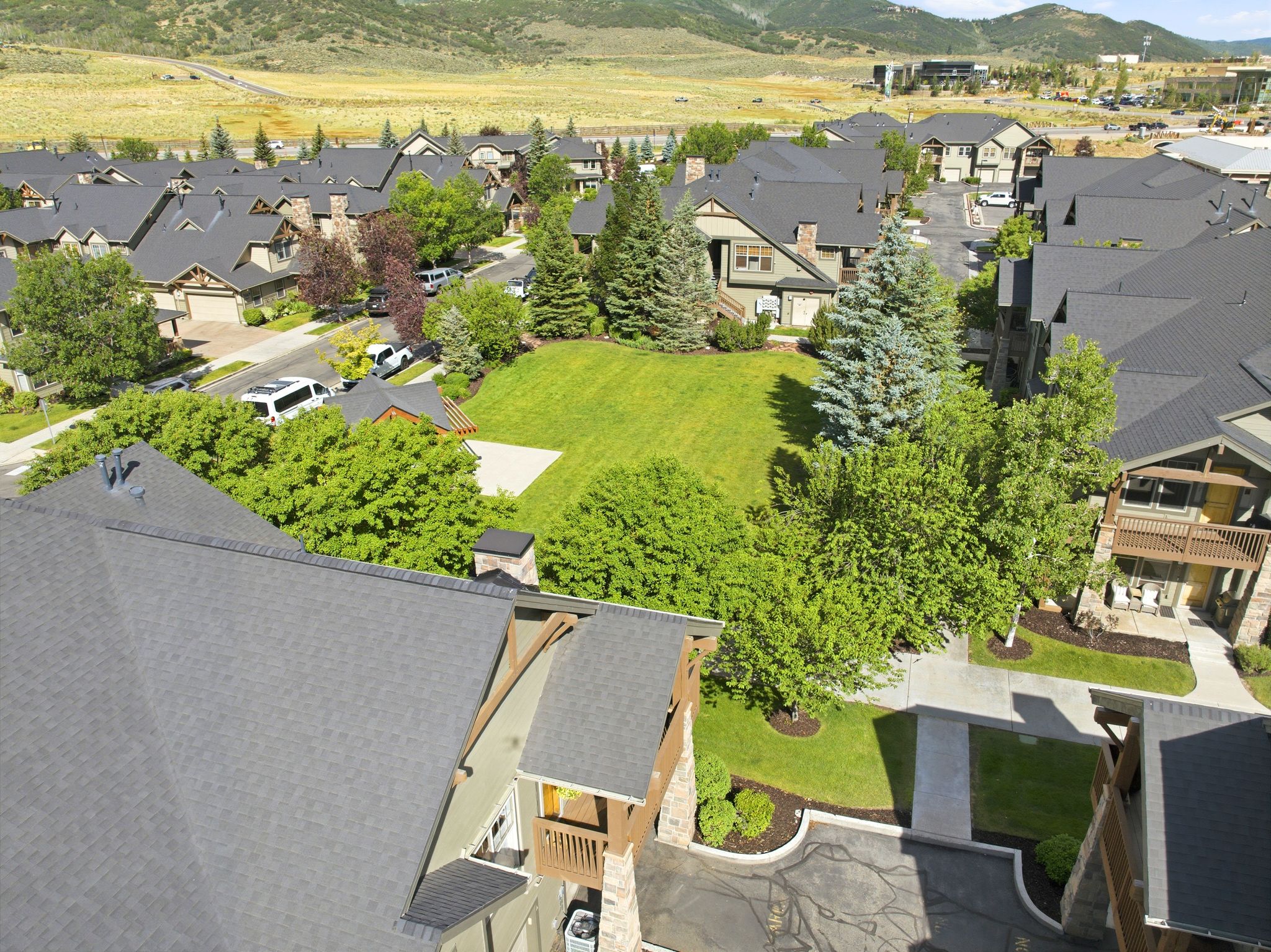 Residential community featuring a variety of properties with dark shingled roofs and extensive landscaping