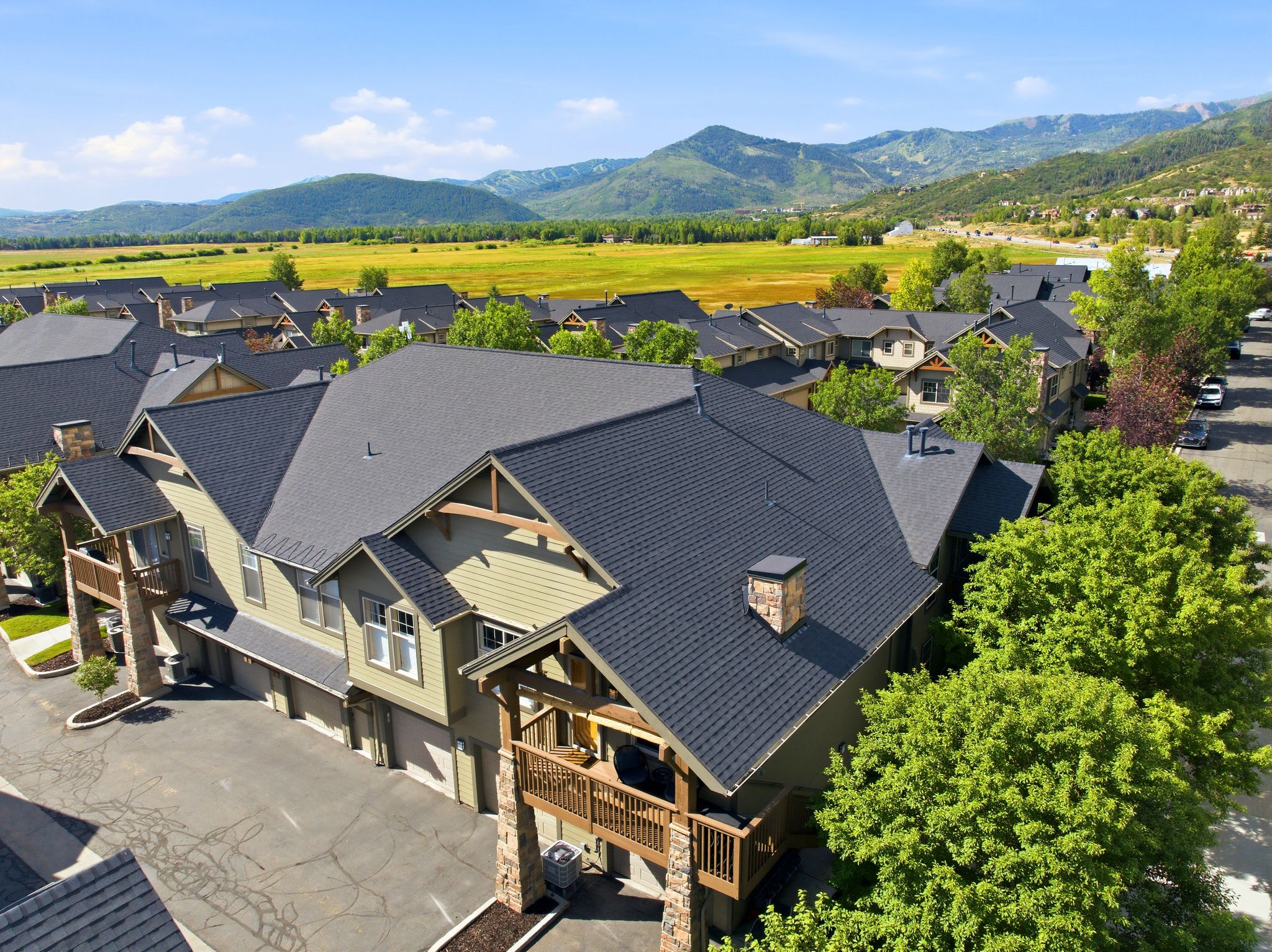 Townhome-style exterior with pitched shingle roofing and stone column accents