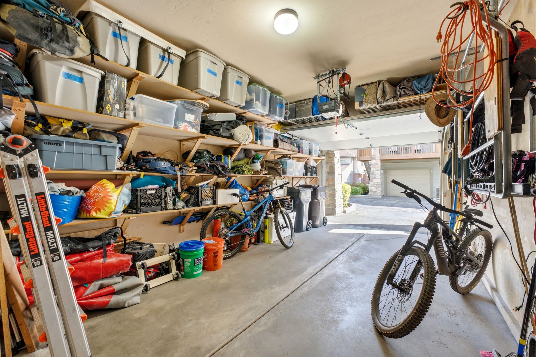 Garage featuring extensive built-in shelving, a concrete floor, overhead lighting, and an automatic garage door opener