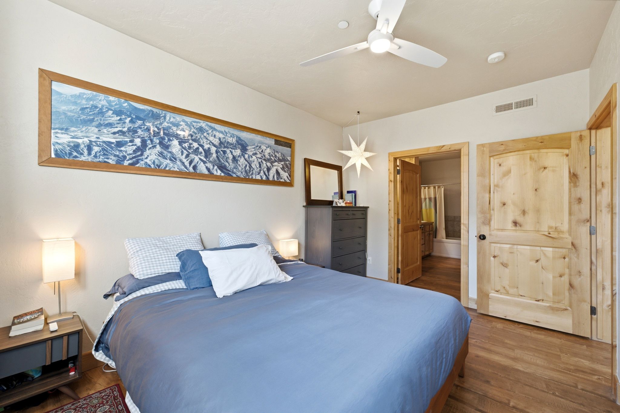 Bedroom featuring wood-finish flooring, natural wood doors, and a ceiling fan with integrated lighting