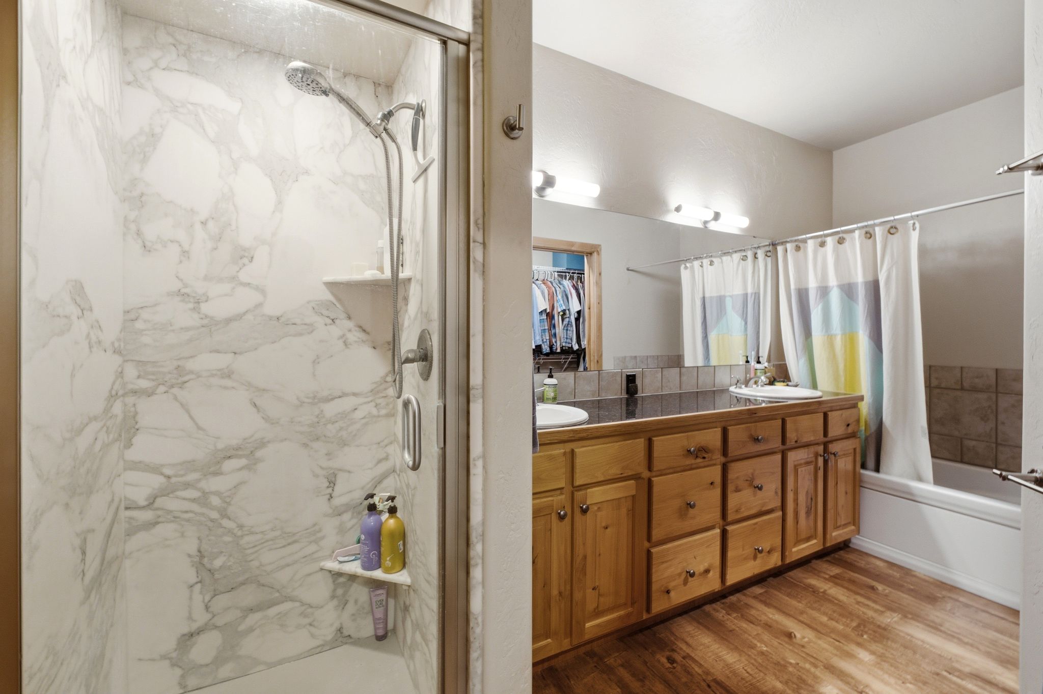 Walk-in shower with marble-look surround, clear glass enclosure, and built-in shelving