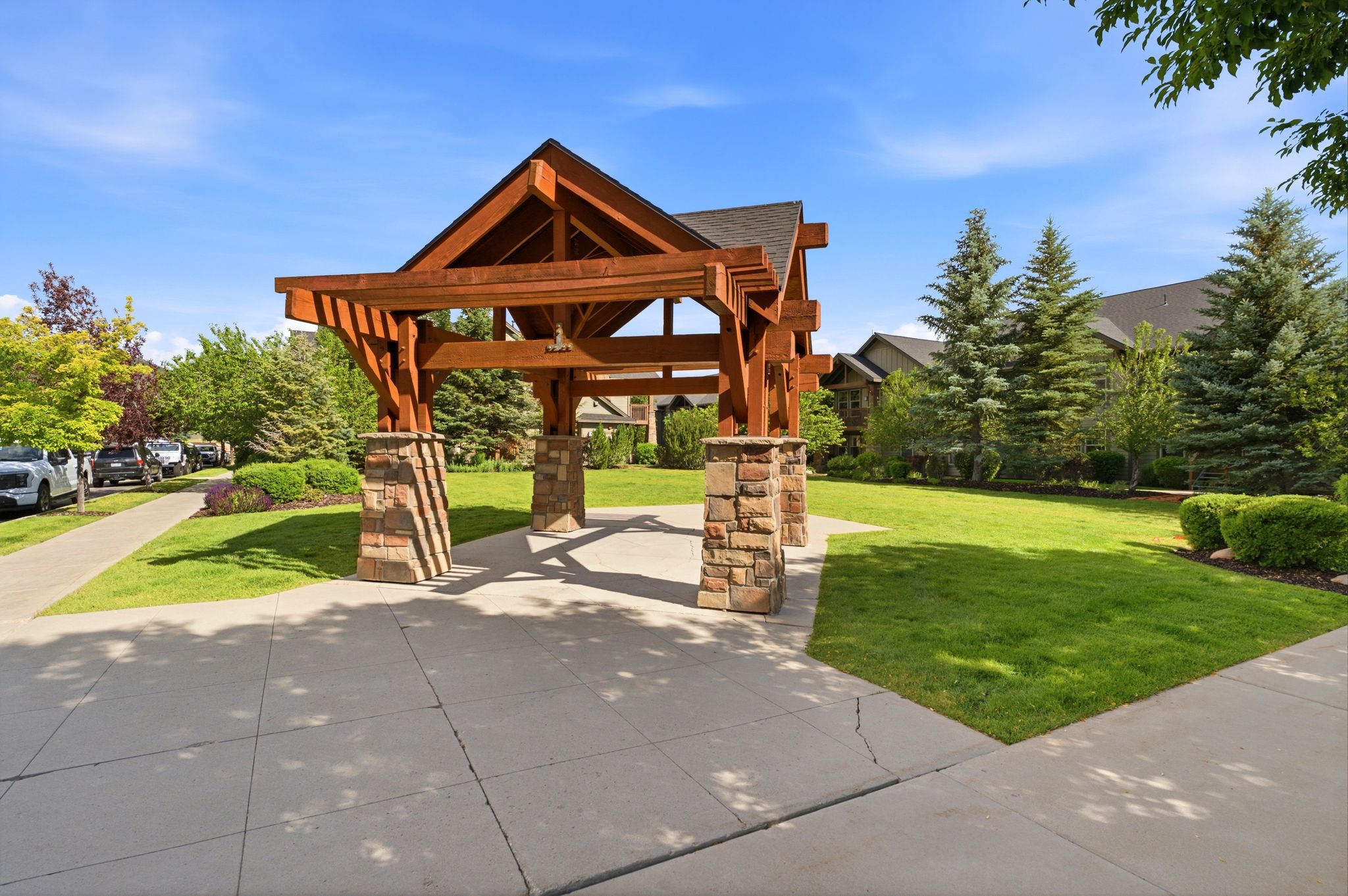 Architectural wood pergola with stone-clad bases, set on a concrete pad
