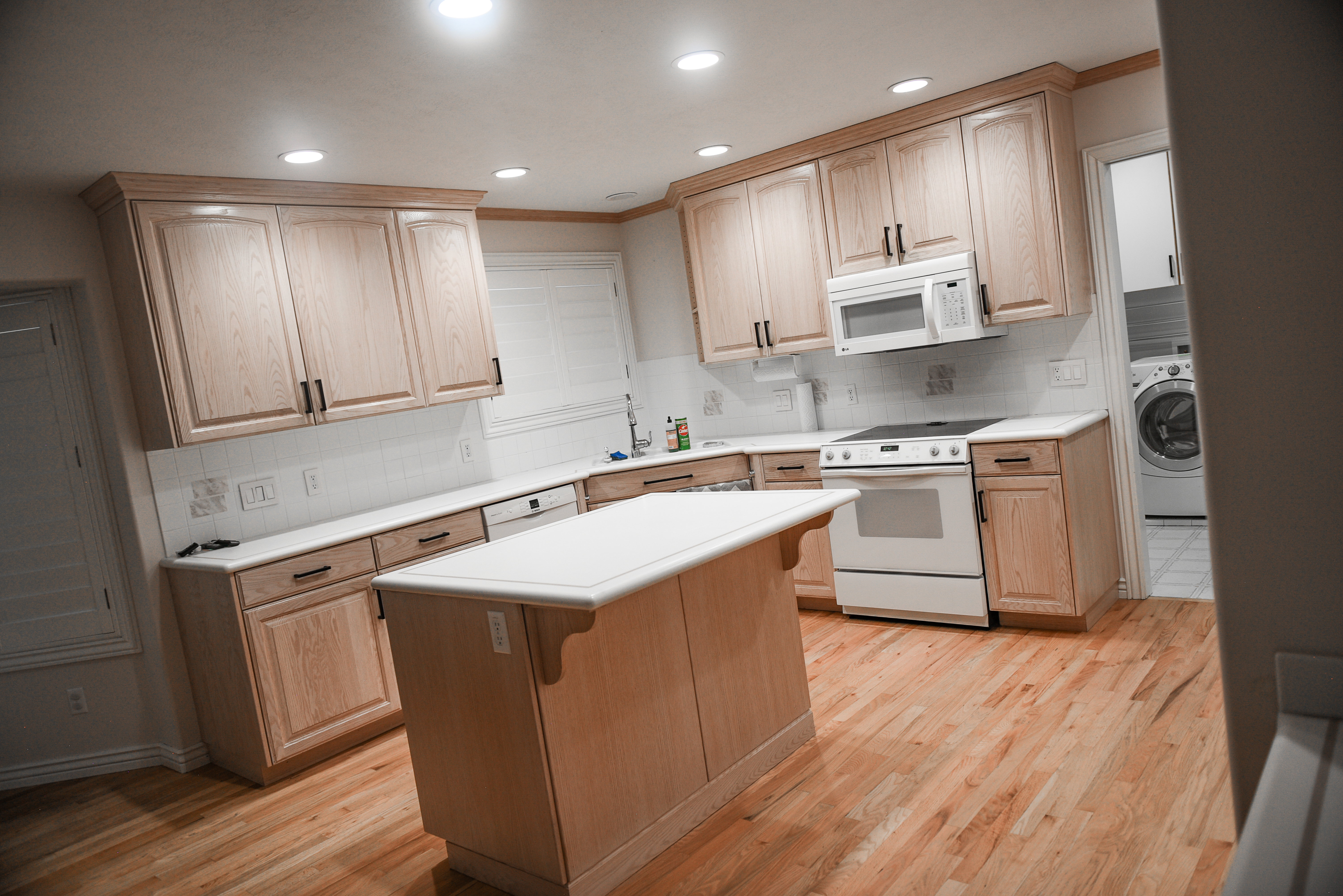 Kitchen featuring light wood cabinetry with dark hardware, white countertops, and a subway tile backsplash