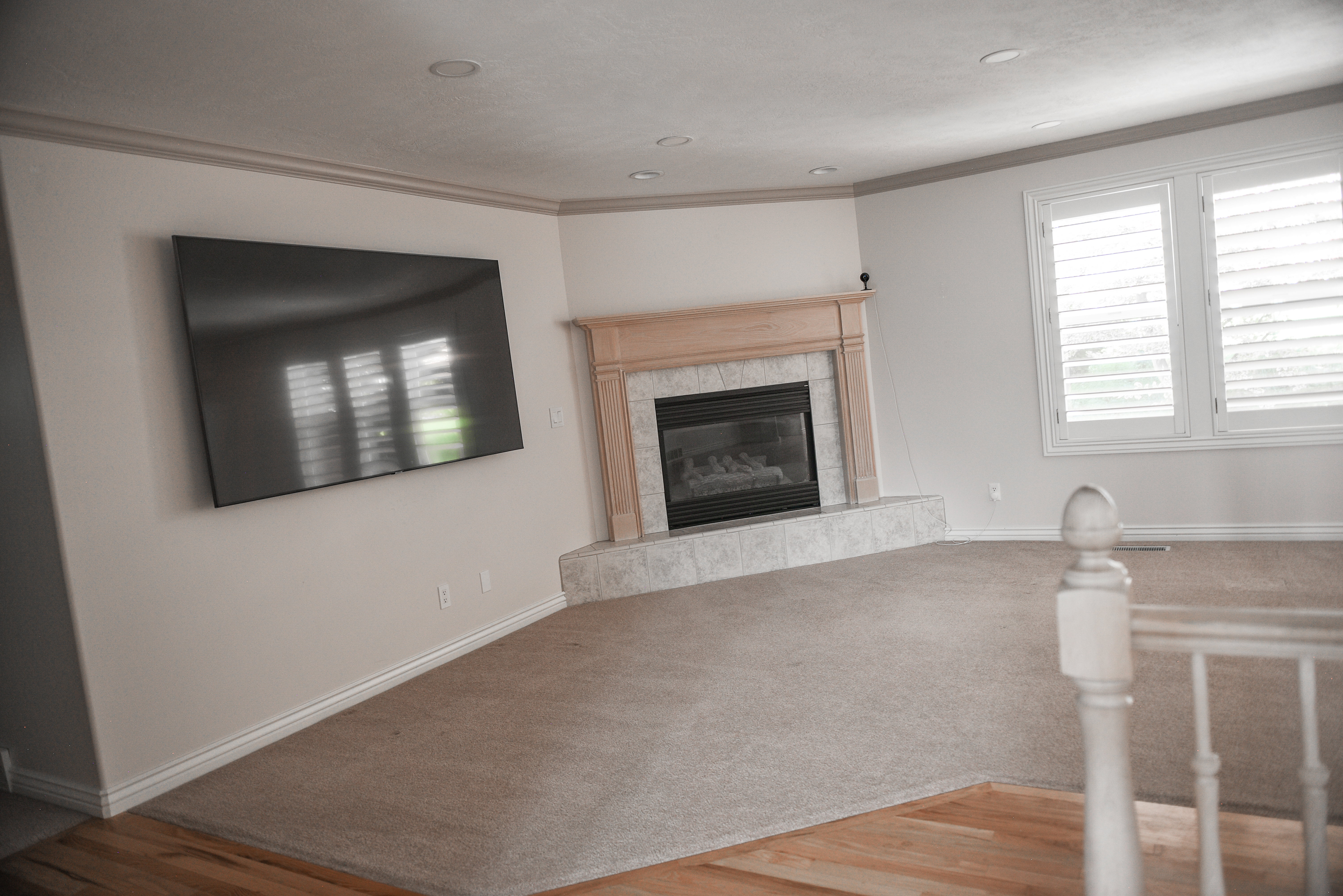 Living area featuring a gas fireplace with a wood mantle and tile surround, recessed lighting, and plantation shutters