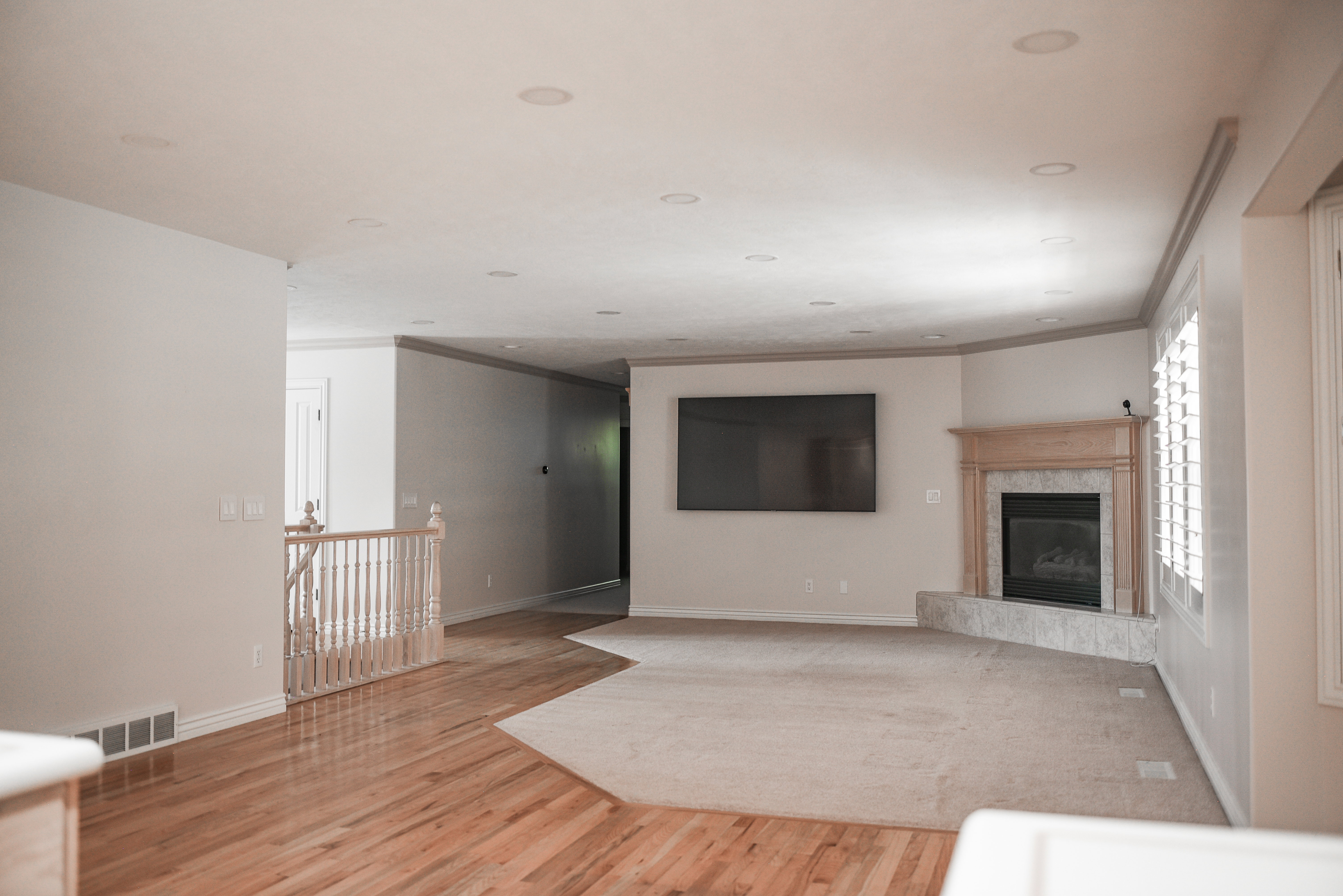 Spacious interior featuring a gas fireplace with a wood mantel and stone surround, wood-finish flooring, recessed lighting, and white plantation shutters