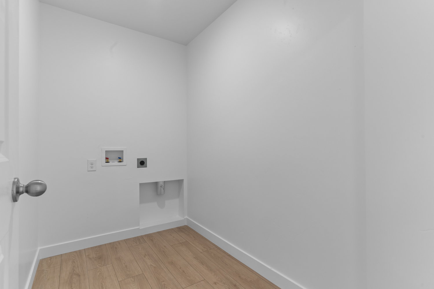Dedicated utility space featuring light wood-finish flooring, white walls, and bright white trim