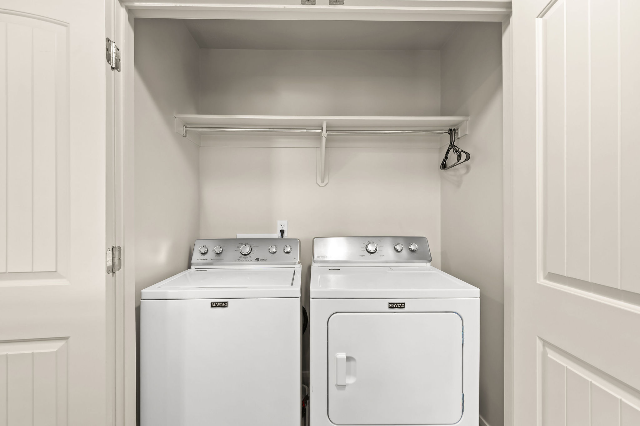 Dedicated laundry closet featuring a top-load washing machine, front-load dryer, upper shelf, and hanging rod