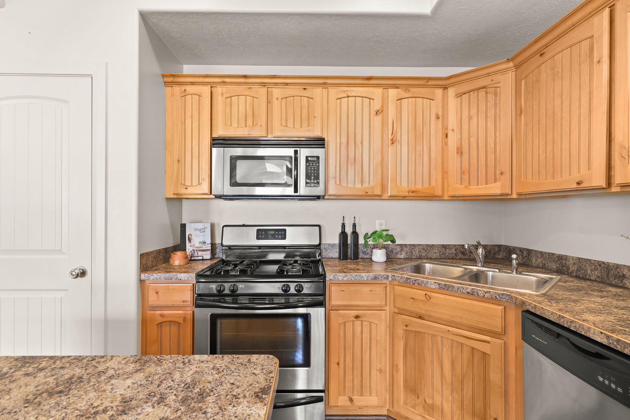 Kitchen featuring wood-finish cabinetry, stainless steel range, stainless steel microwave, double basin sink, and laminate countertops