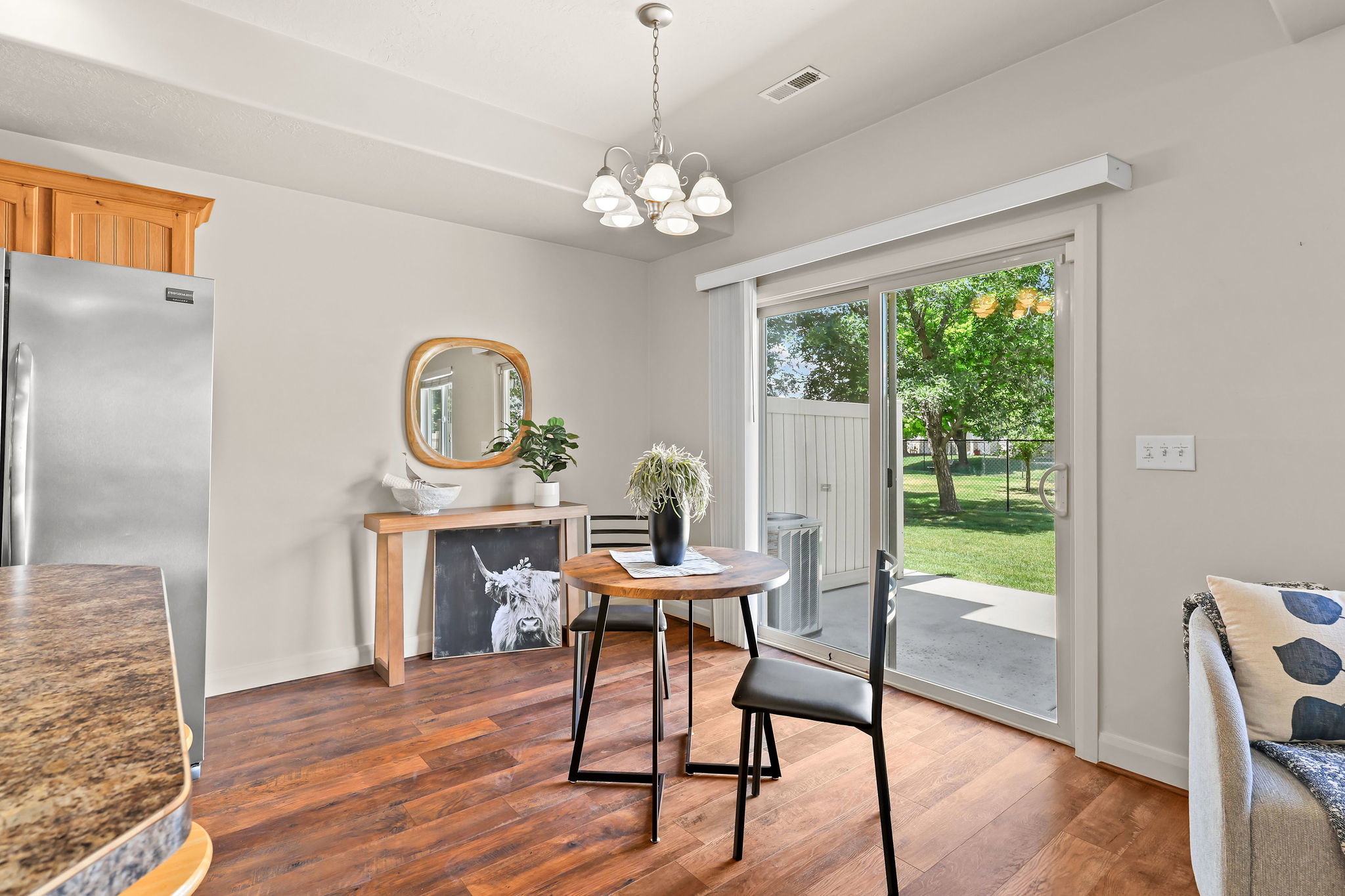 Dining area featuring laminate wood flooring, a contemporary chandelier, and direct patio access through sliding glass doors