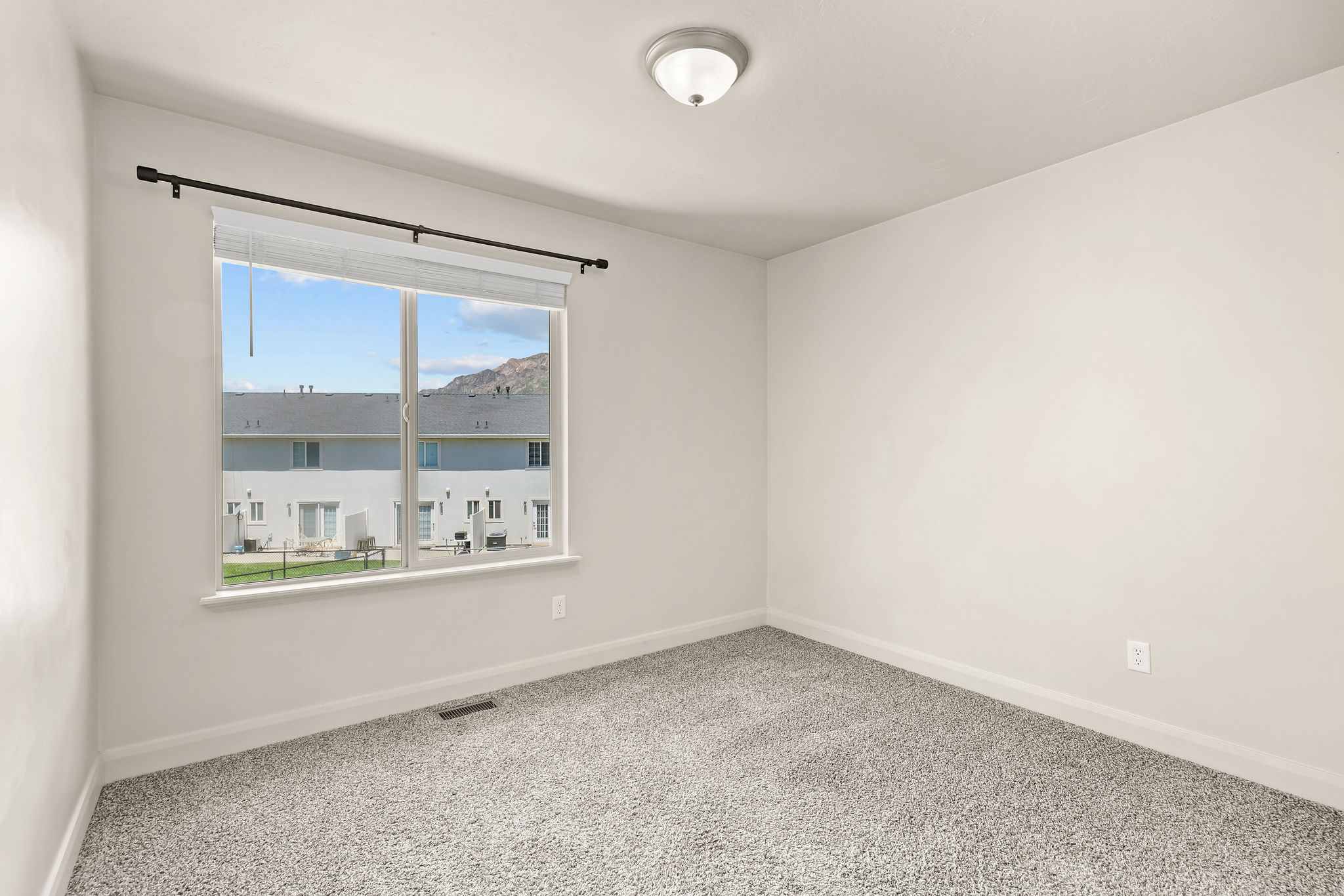 Bright room featuring a large window, neutral carpeting, and a flush-mount ceiling light