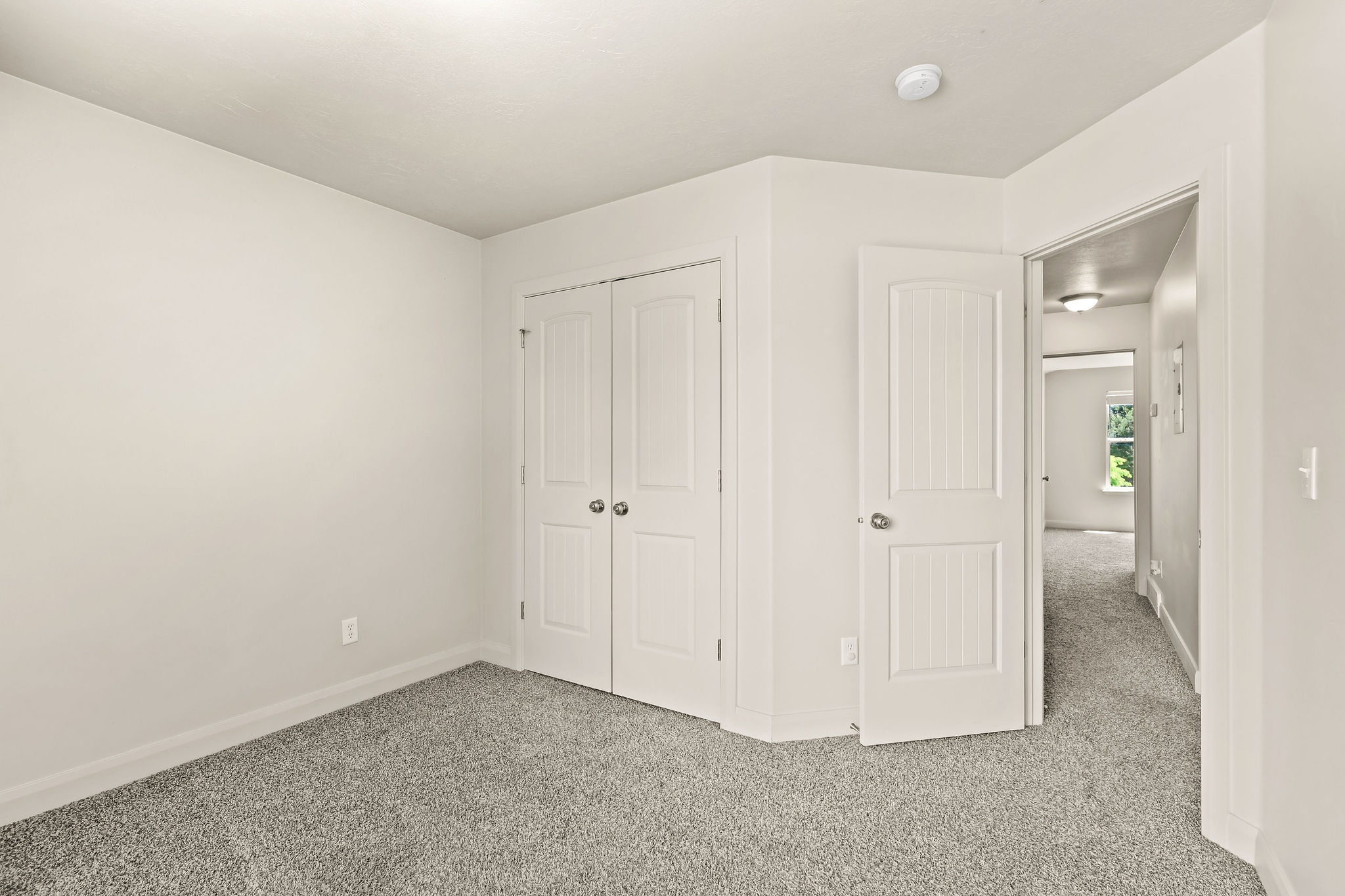 Carpeted room with a double-door closet and white trim