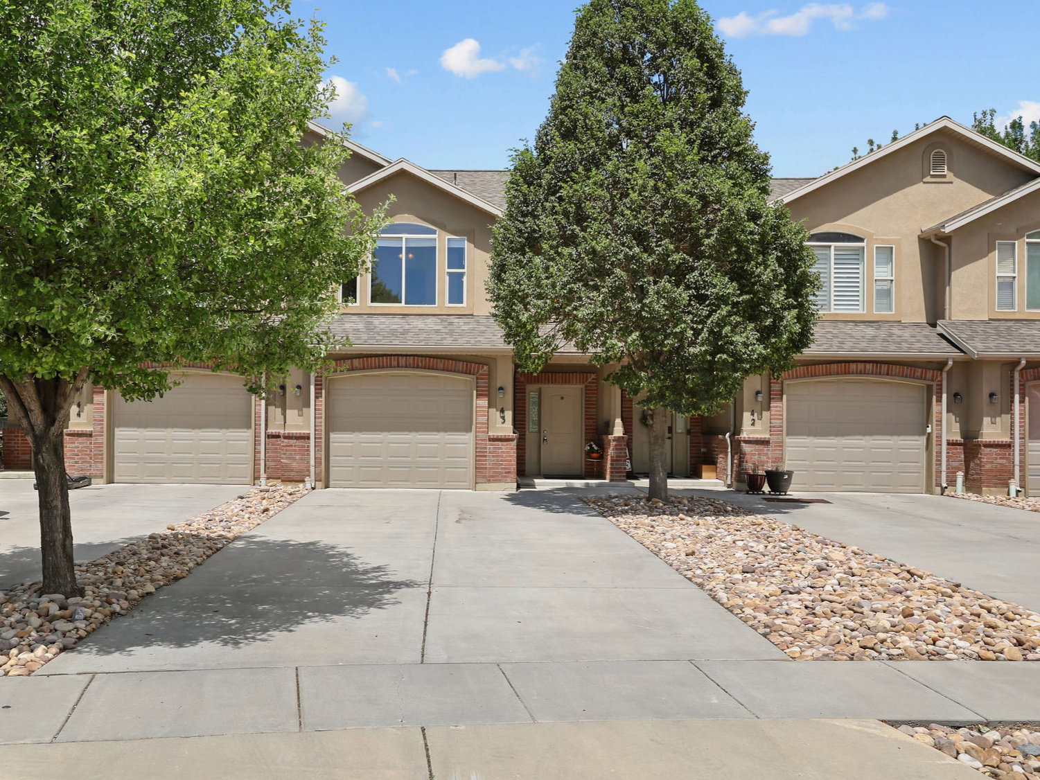 Two-story home featuring a stucco facade with brick accents and arched garage entries