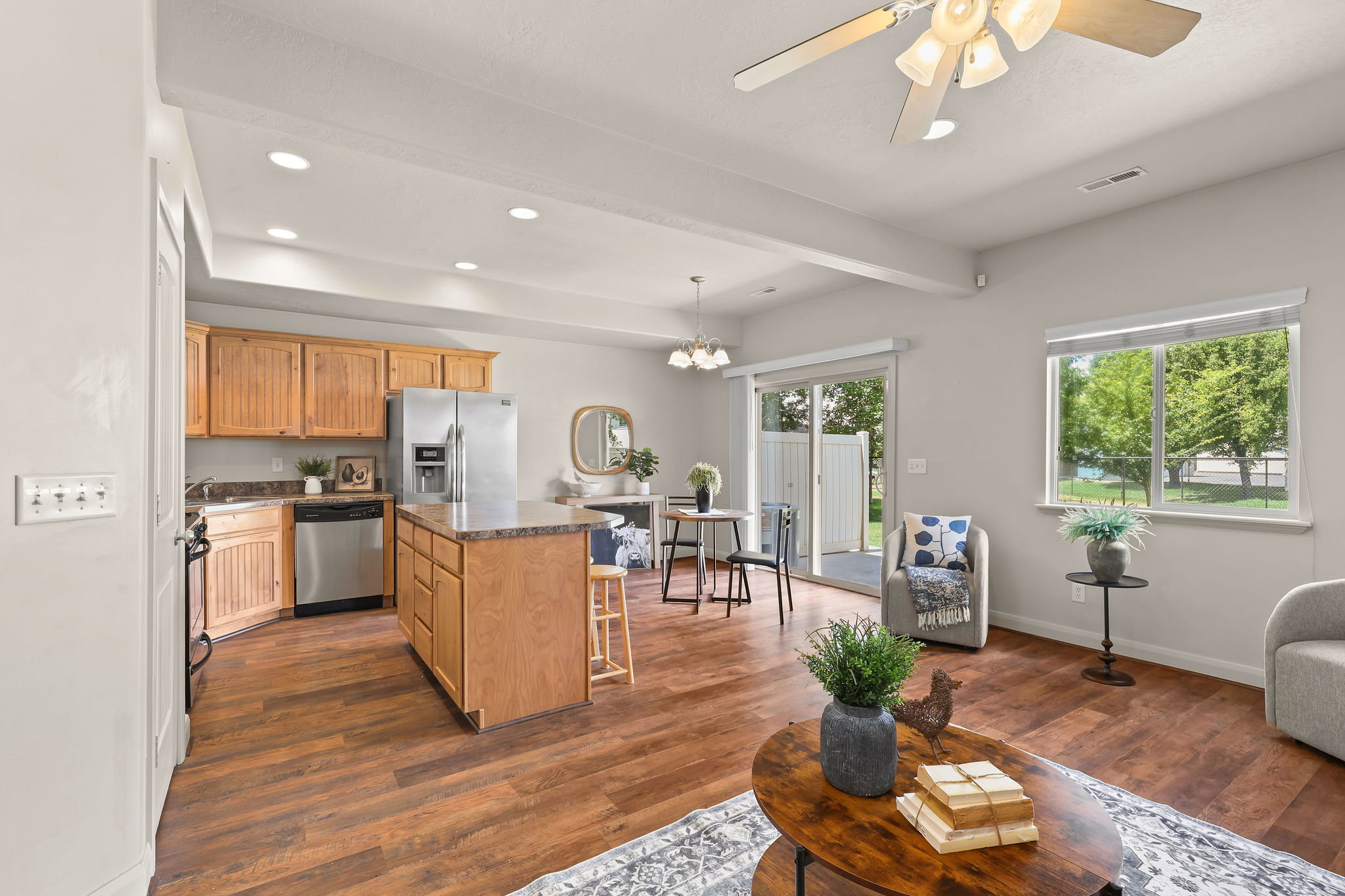 Open-concept living area with wood-finish flooring, a kitchen island with seating, and stainless steel appliances