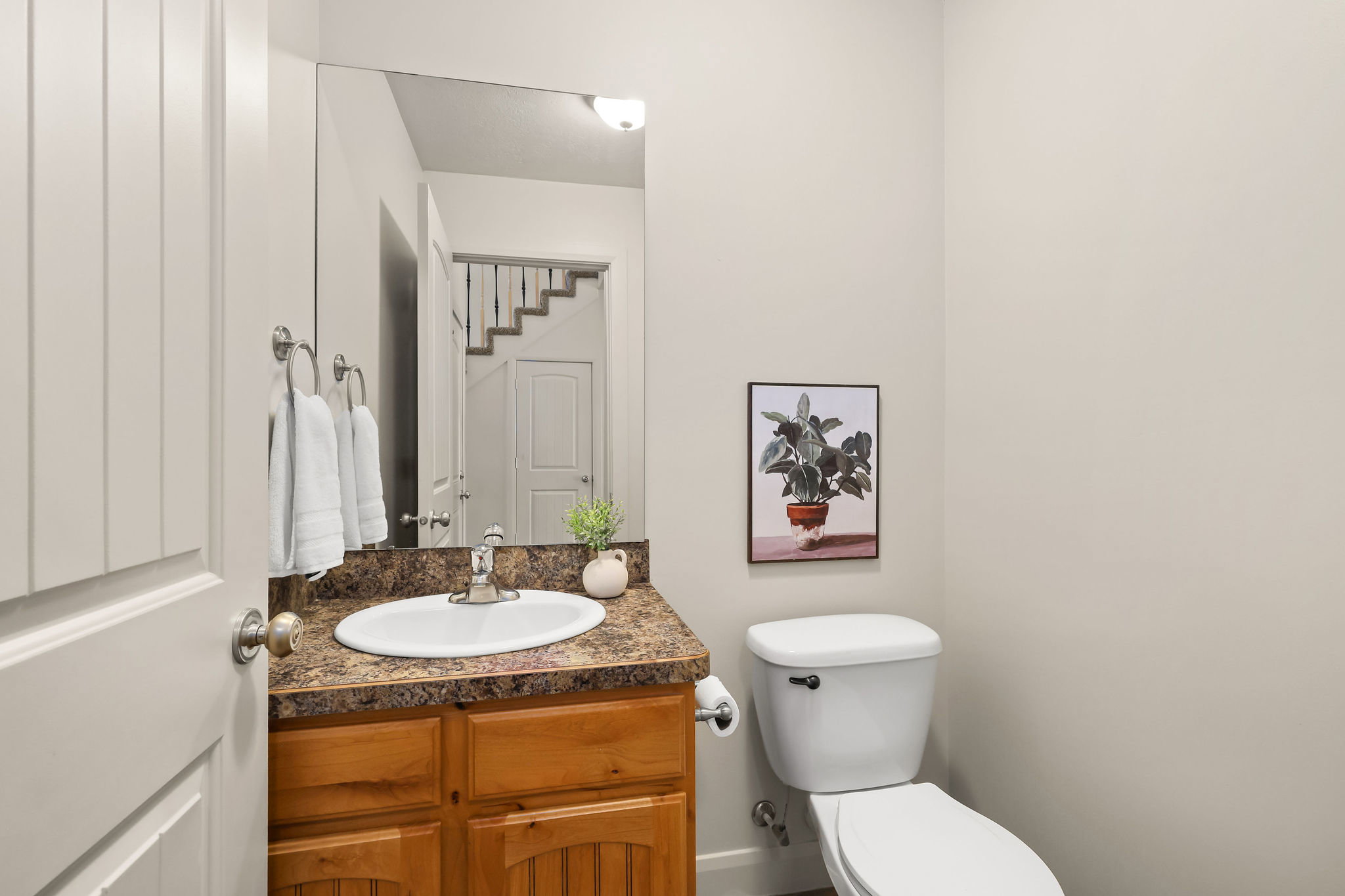 Powder room featuring a wood vanity with a stone-look countertop, undermount sink, and wall-mounted mirror