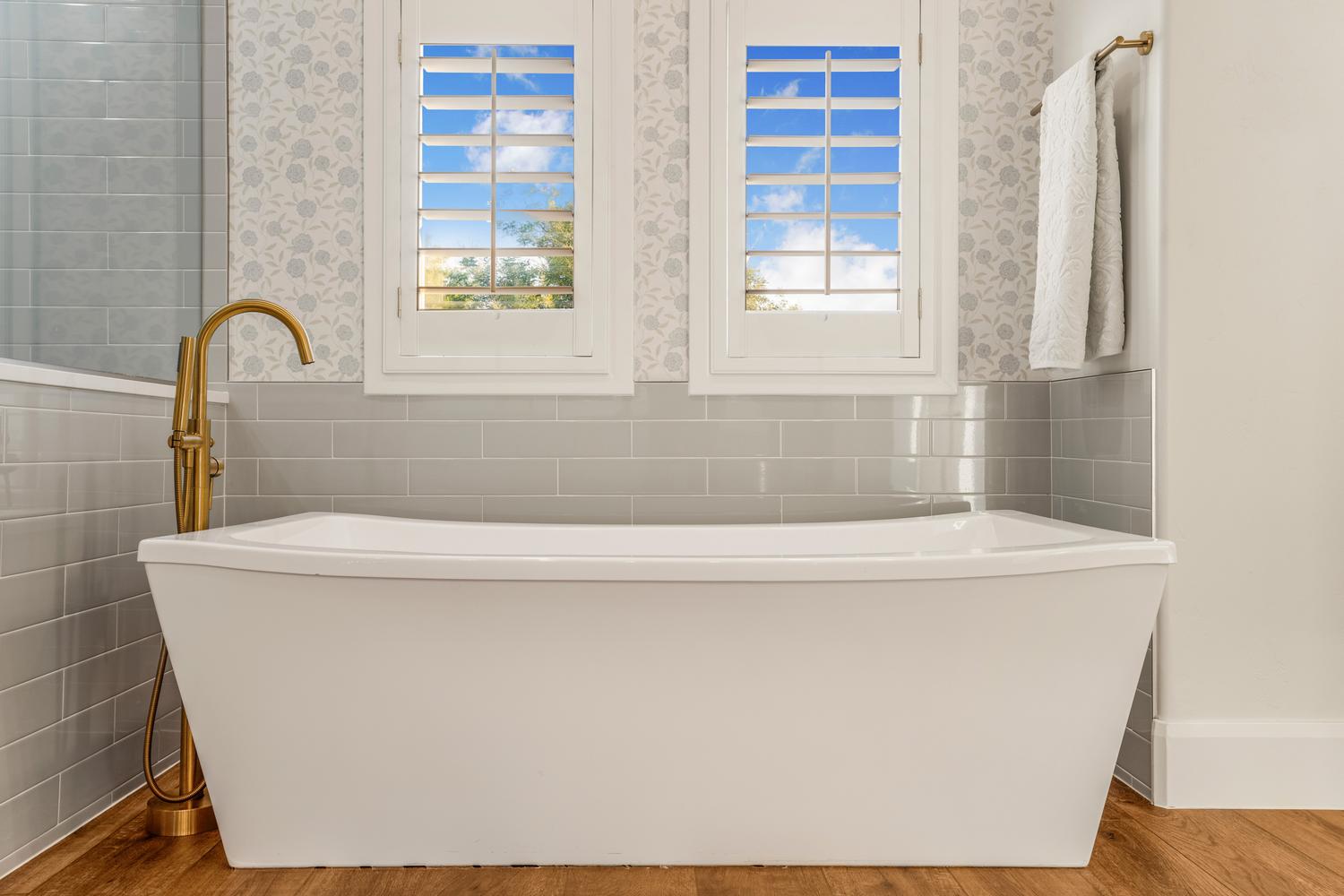 Freestanding white bathtub with a brass floor-mounted faucet