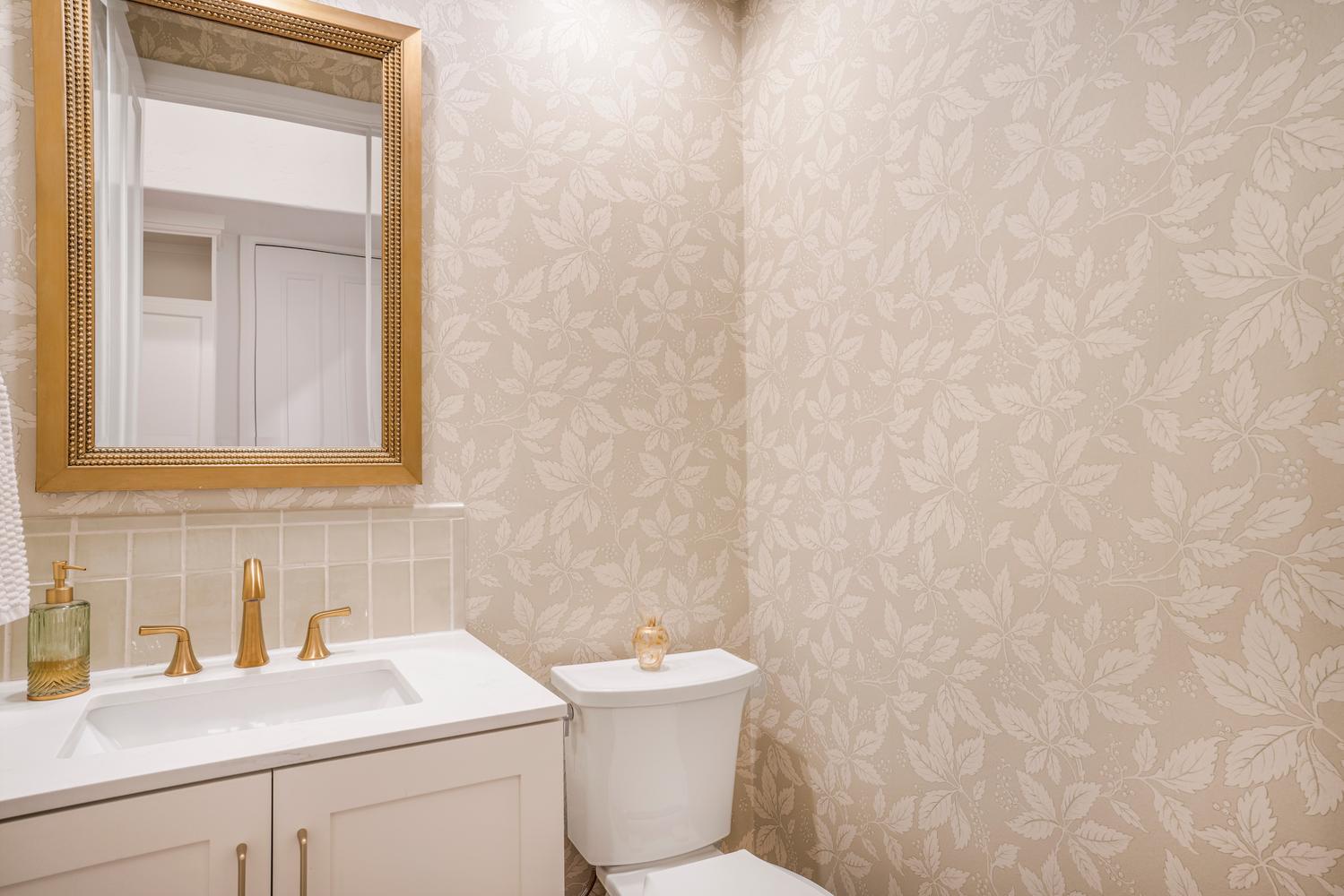 Bathroom featuring a vanity with a white countertop, gold-finish faucet, and a gold-framed mirror