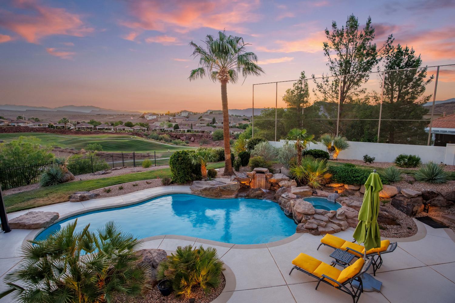 Resort-style pool area featuring a freeform swimming pool, rock waterfall, and integrated spa