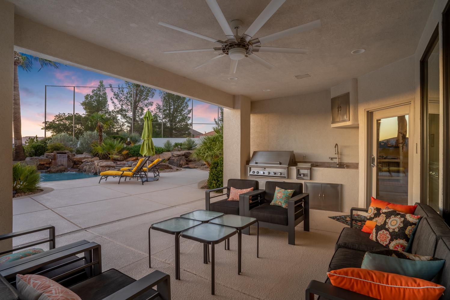 Covered patio with integrated outdoor kitchen, ceiling fan, built-in grill, and sink with stainless steel cabinetry