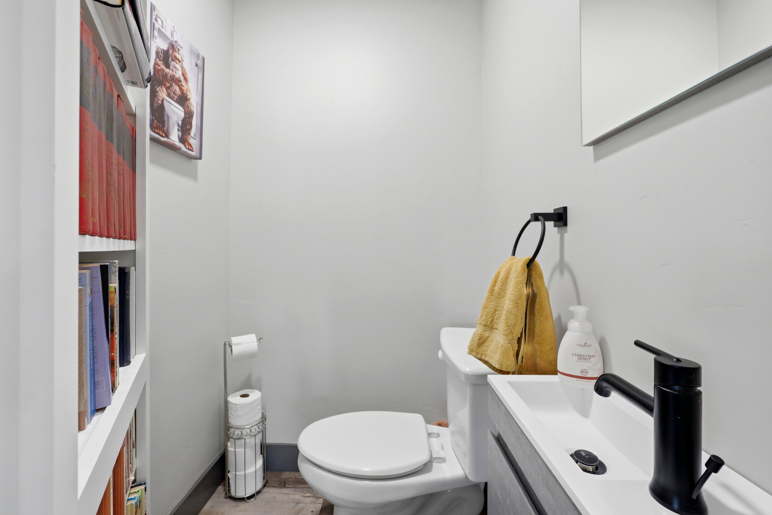 Compact powder room featuring a wall-mounted sink with a matte black faucet, a white toilet, and light gray walls